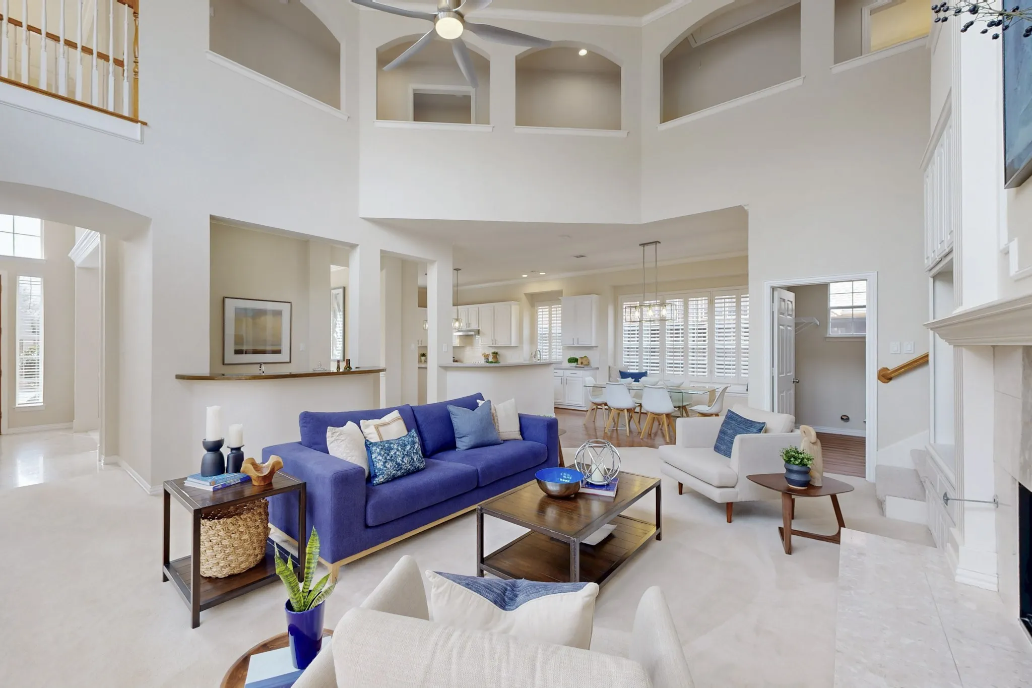 Living room featuring soaring ceilings, expansive open sightlines, a fireplace centerpiece, and seamless flow to the kitchen and dining areas