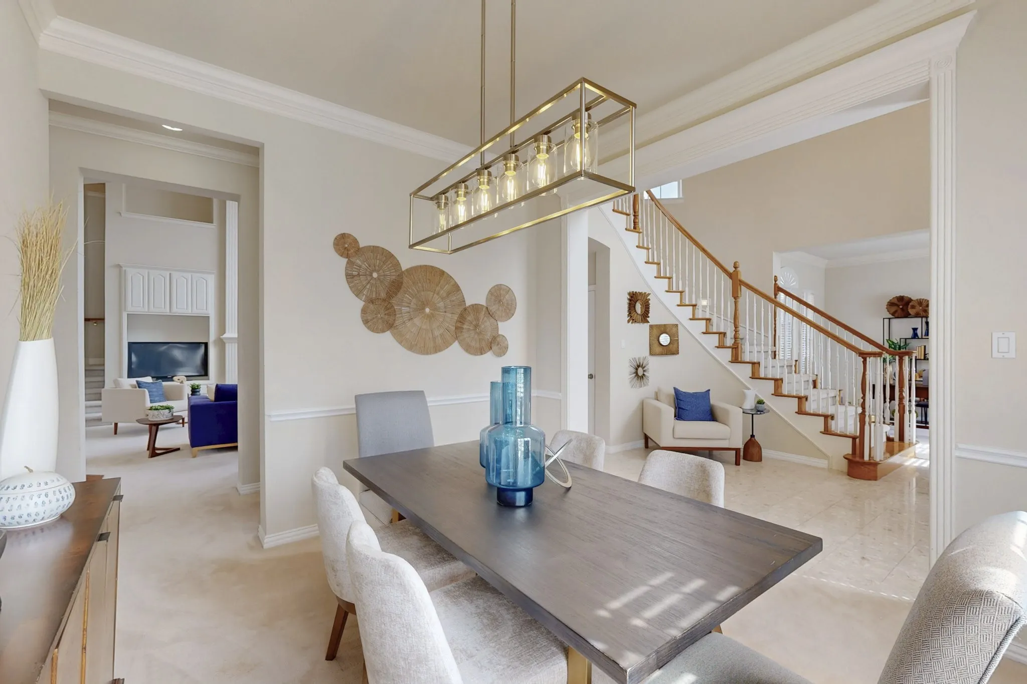 Formal dining room featuring crown molding, designer lighting, and seamless views of the grand staircase and adjacent living spaces