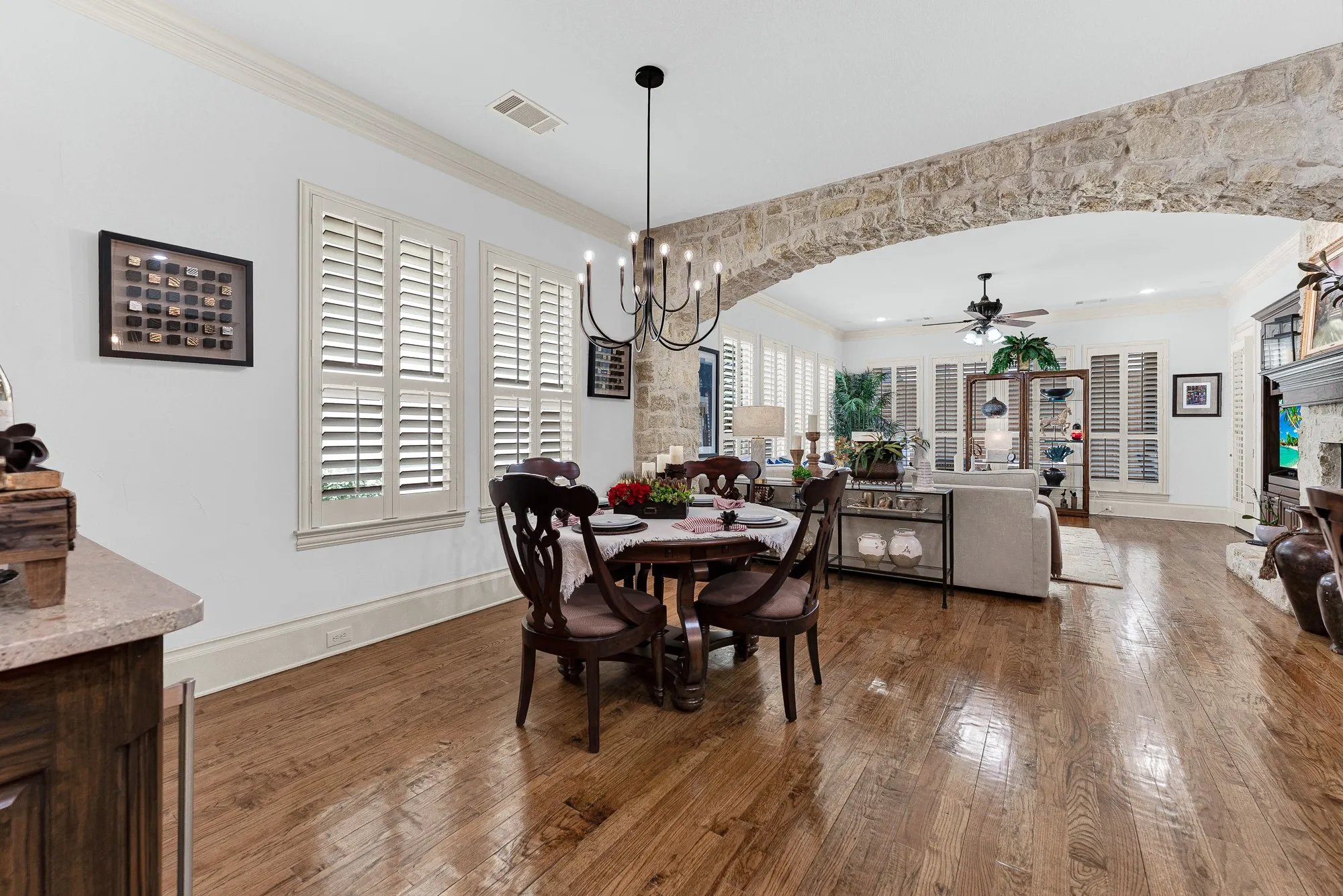 An expansive stone archway naturally divides the casual dining space while allowing morning light to spill across gleaming hardwood floors. Gather here for a quiet, sunlit breakfast before the rest of the house stirs awake.
