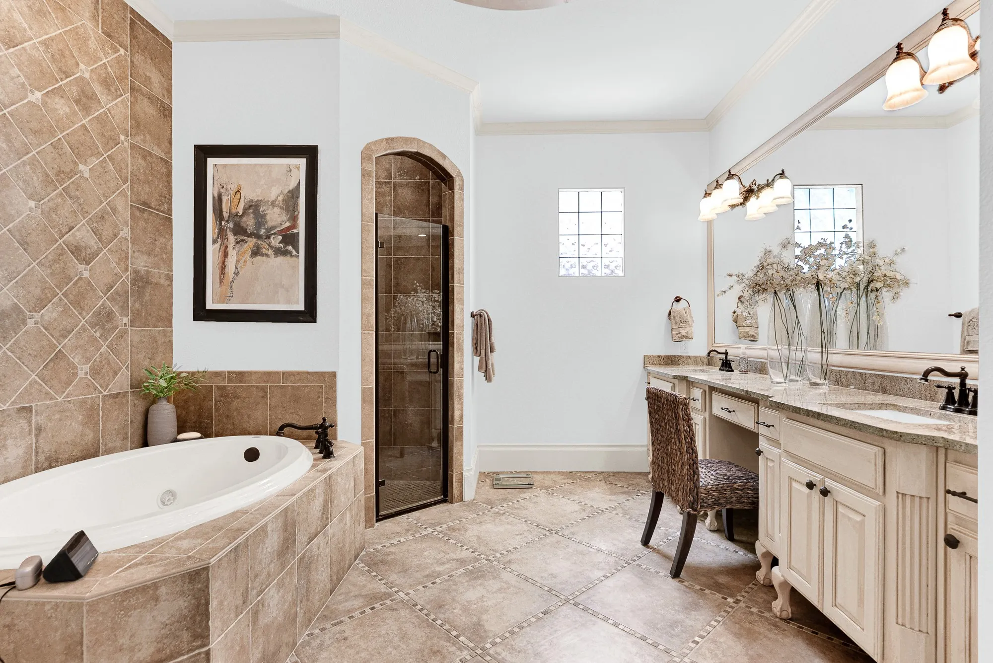 An arched glass shower entry sits beside a jetted soaking tub framed by rich, diagonal stone tilework. Unwind with a warm, spa-like bath after a demanding workday.
