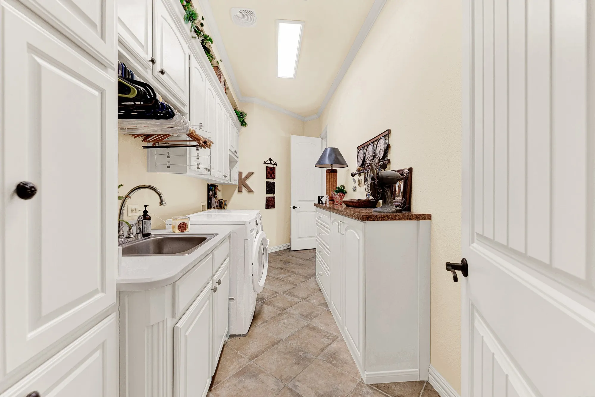 An integrated utility sink and dual storage banks line the pass-through hallway leading directly to the primary suite. Tackle household chores with ease in a bright, thoughtful layout designed for seamless daily flow.