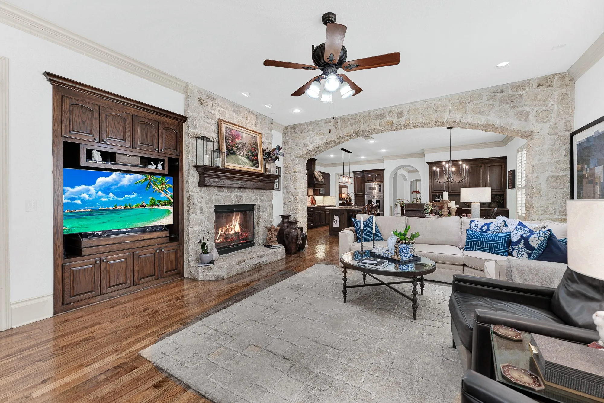 A rustic stone fireplace with a raised hearth stands beside detailed custom cabinetry. Curl up by the flickering fire for a cozy movie night after a long day