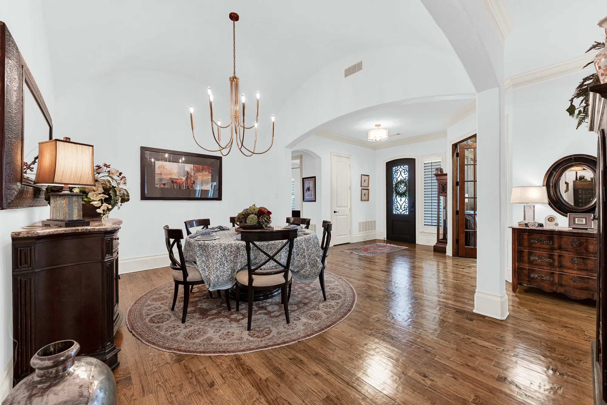 A dramatic groined vault ceiling catches light softly, adding architectural grandeur above rich hardwood floors. Imagine setting the table for holiday gatherings, surrounded by warm, glowing light and elegant spatial flow