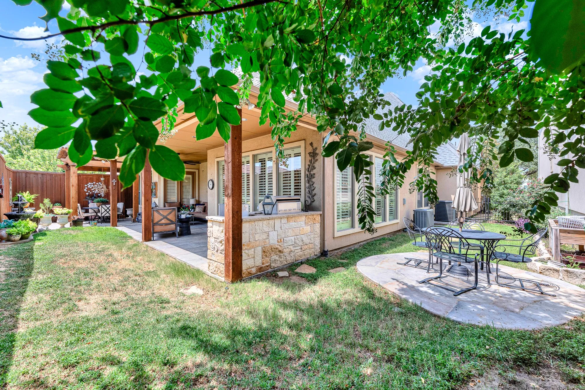 Rustic wooden support beams frame seamless transitions between open sky and sheltered outdoor living spaces. Picture grilling up a summer feast while loved ones relax nearby under leafy canopies.