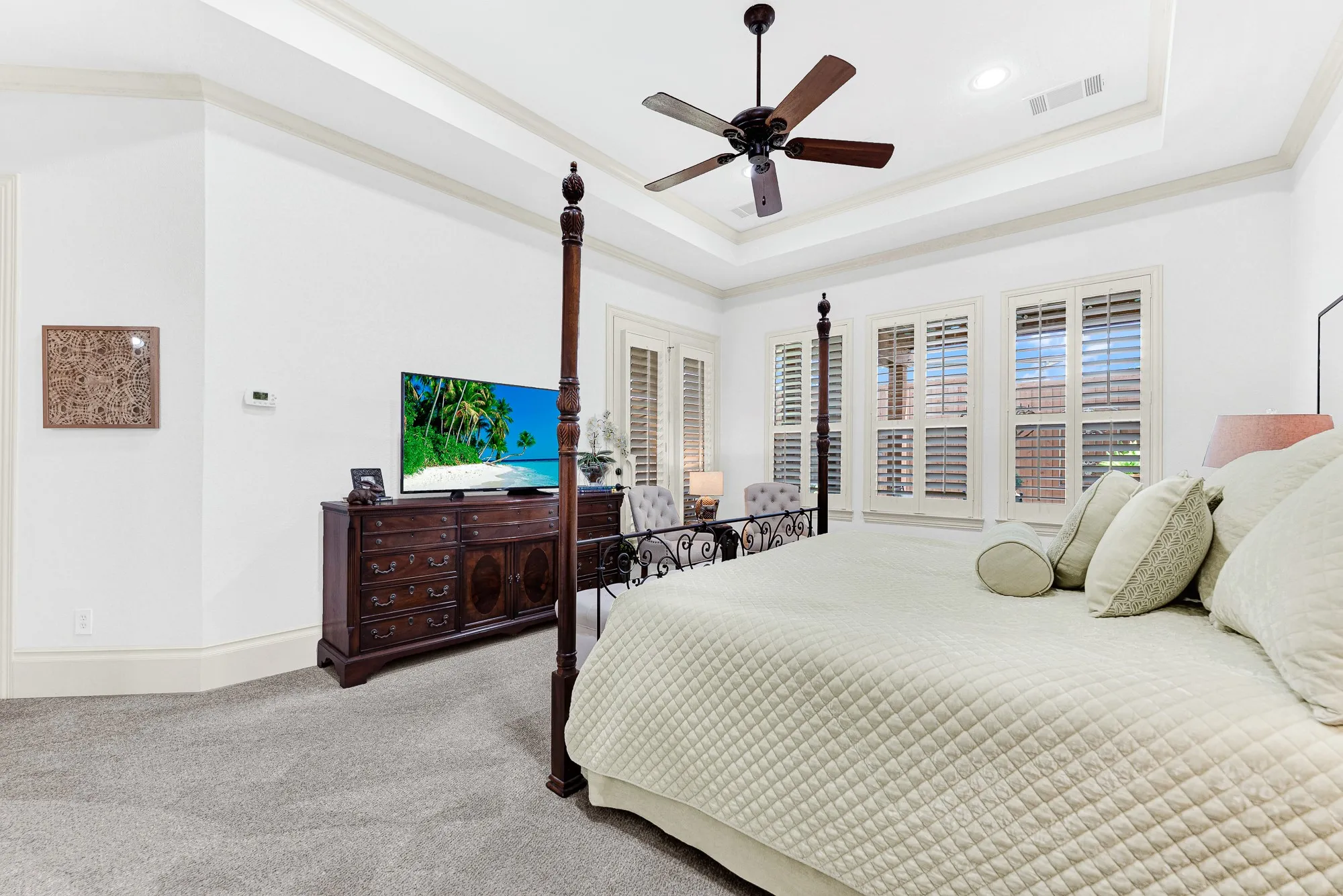 Deep crown moldings highlight the room's generous proportions and seamless connection to private outdoor access. Start your mornings feeling completely restored in a spacious, sun-dappled haven