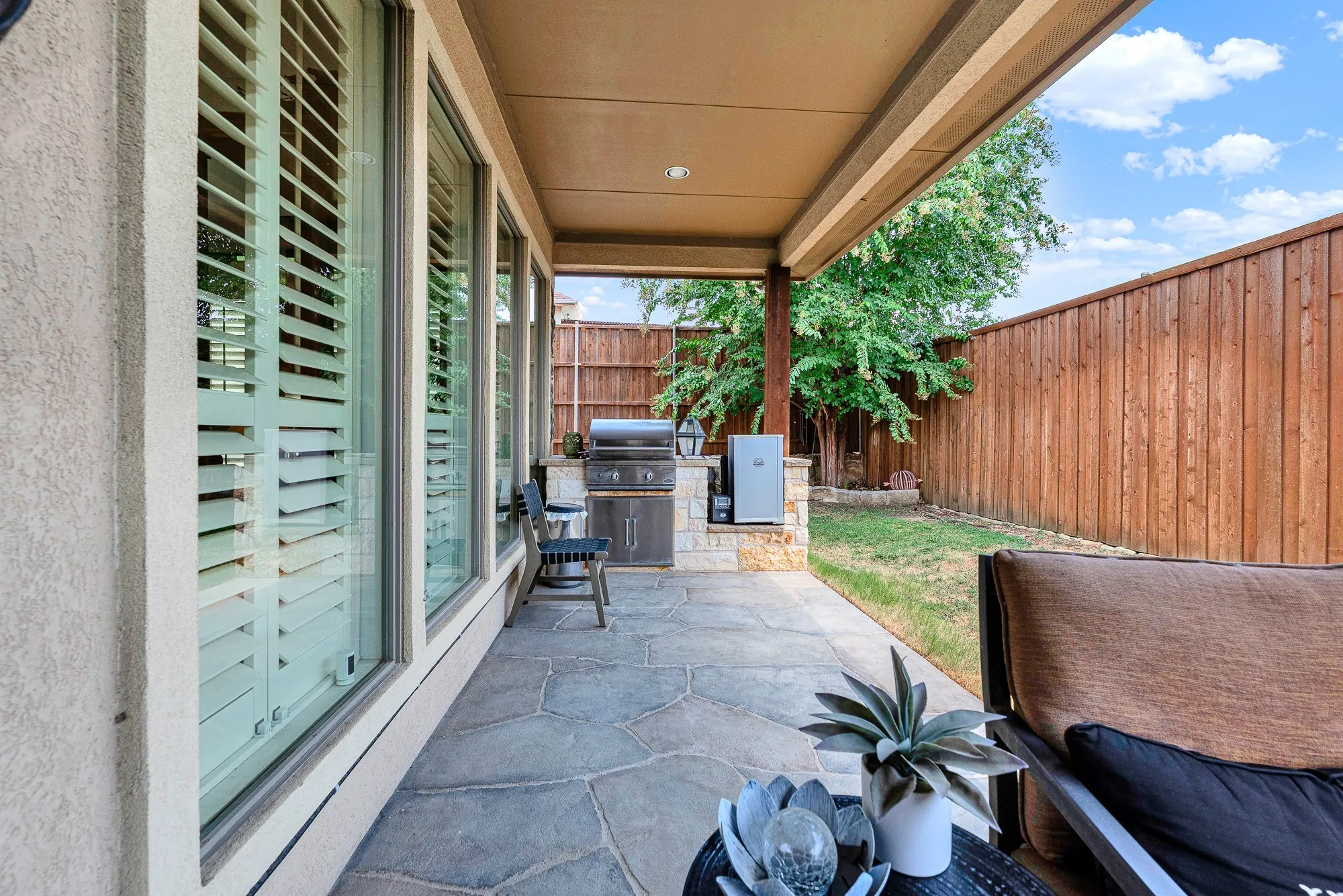 A custom stone island seamlessly integrates a built-in gas grill and electric smoker under the protective roofline. Savor slow-smoked barbecue on game days, enjoying effortless outdoor cooking steps from your back door.