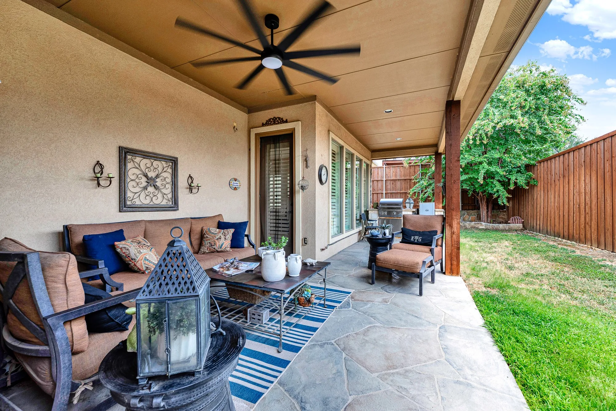 Recessed lighting and a sleek, oversized ceiling fan enhance the spacious overhang, keeping midday breezes circulating over the stamped concrete floor. Kick back with a good book on a quiet afternoon while staying sheltered from the summer sun.