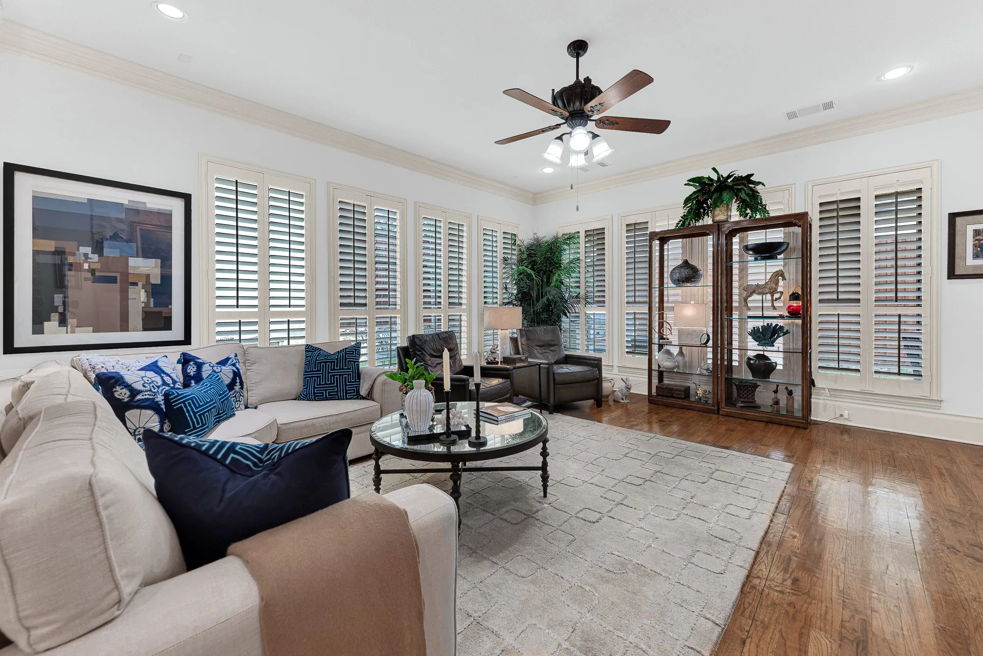 A expansive bank of floor-to-ceiling plantation shutters diffuses soft daylight across rich oak flooring. Unwind with your favorite book as gentle afternoon light filters through the quiet space.