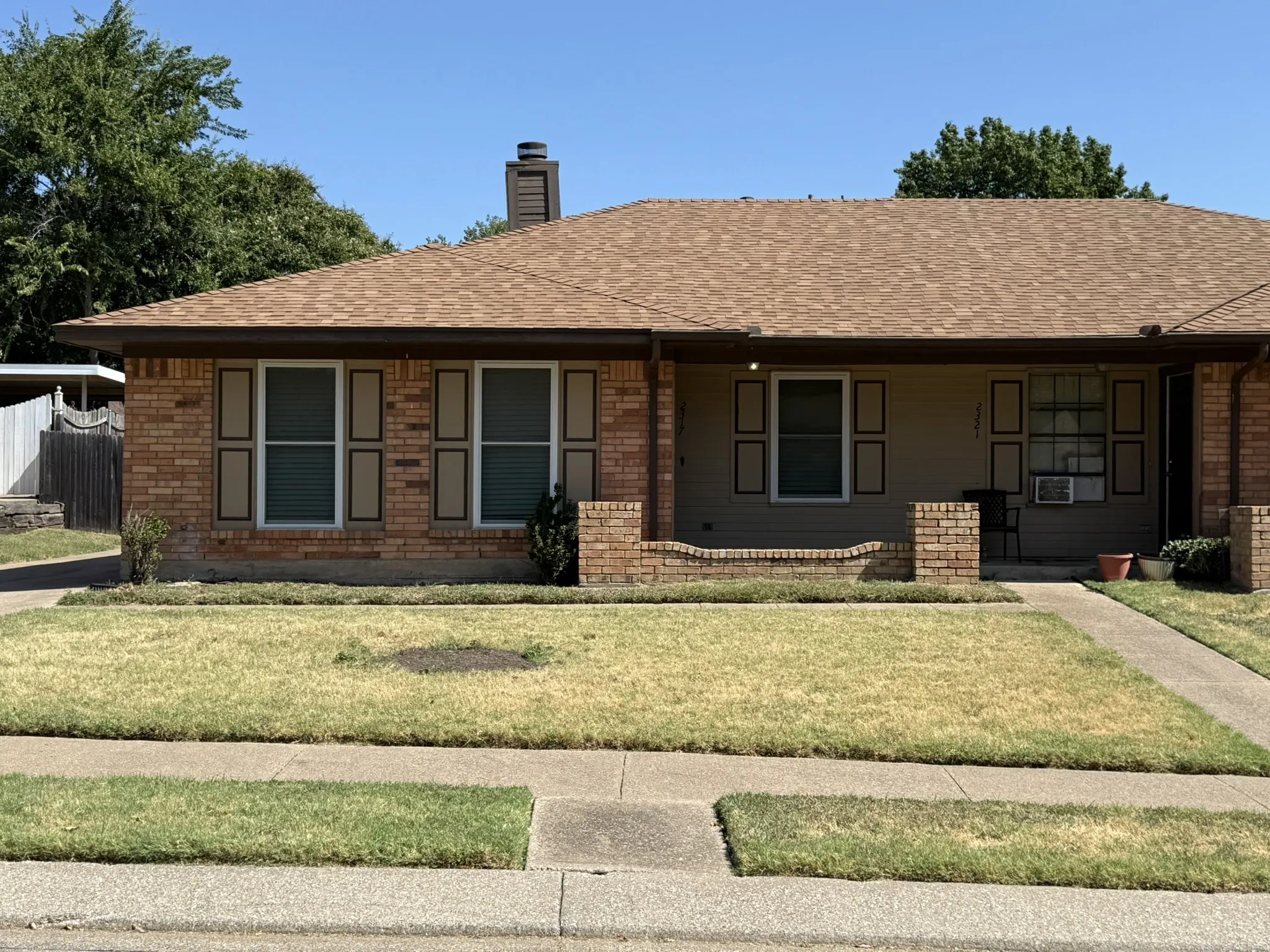 Brick exterior with a shingle roof and decorative shutters