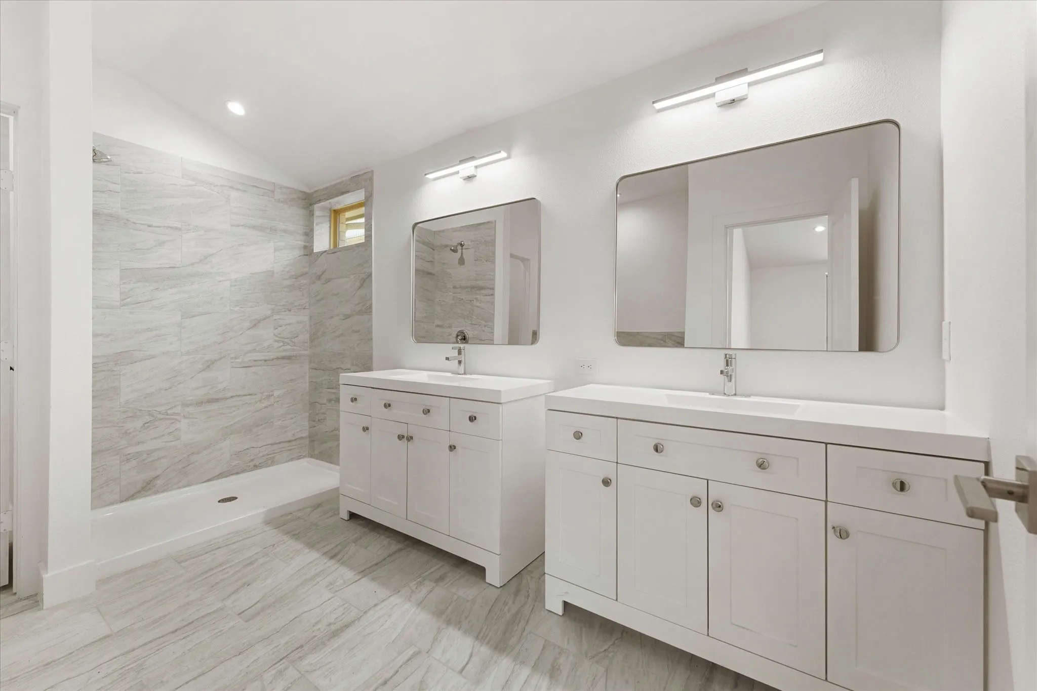 Dual white vanities with integrated sinks, contemporary wall-mounted light fixtures, and coordinating rectangular mirrors