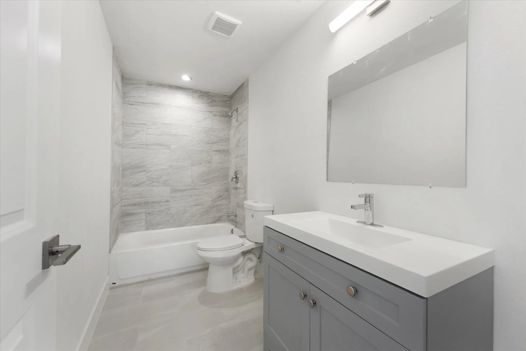 White bathtub and shower combination with light-toned tile surround