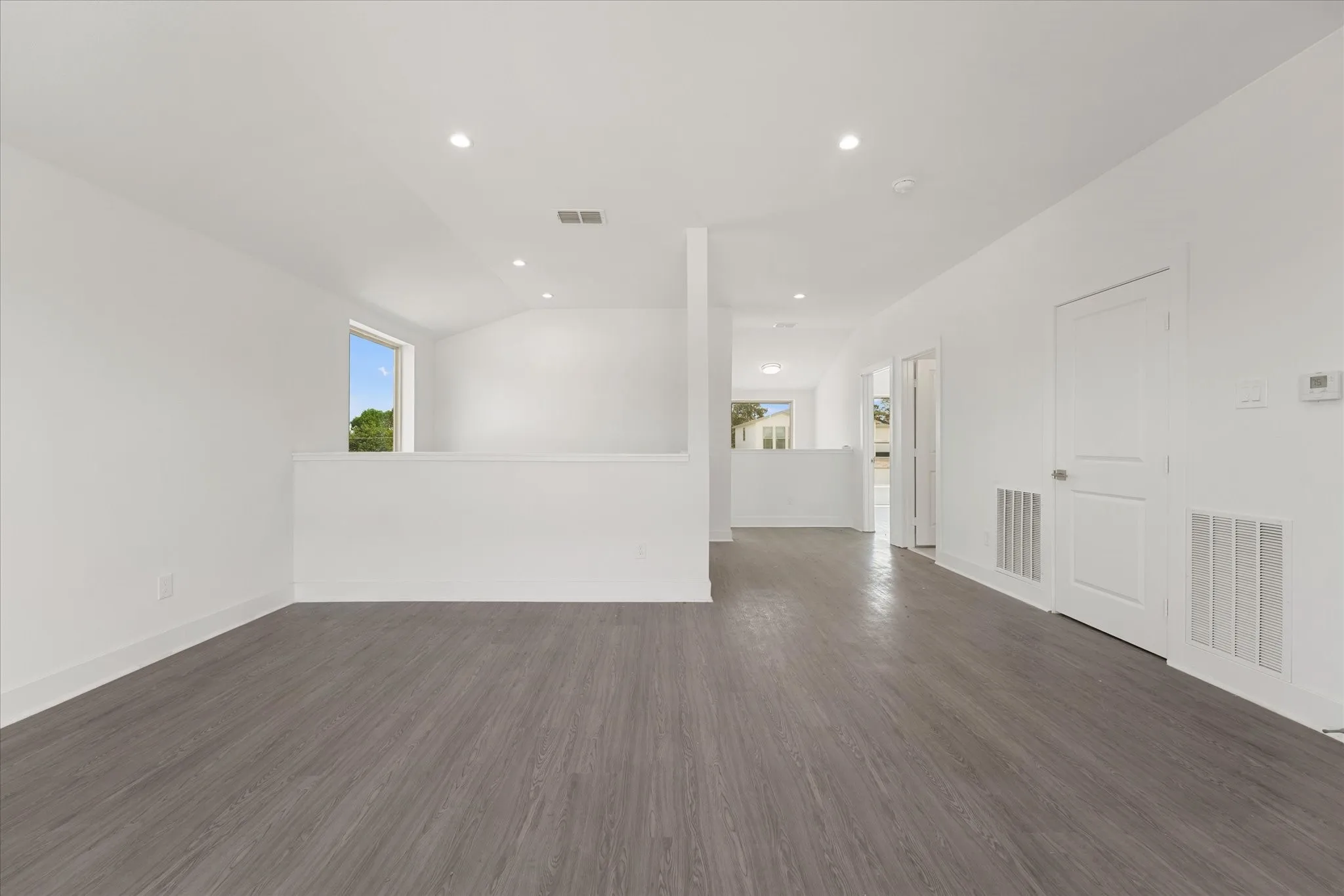 Expansive interior space featuring wood-finish flooring, recessed lighting, and crisp white walls