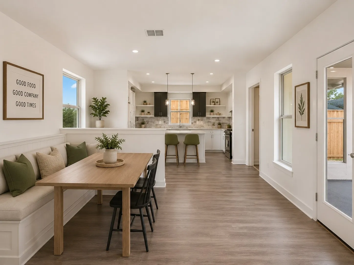 Open-concept layout with wood-finish flooring, built-in dining bench, recessed lighting, and a kitchen featuring dark and light cabinetry