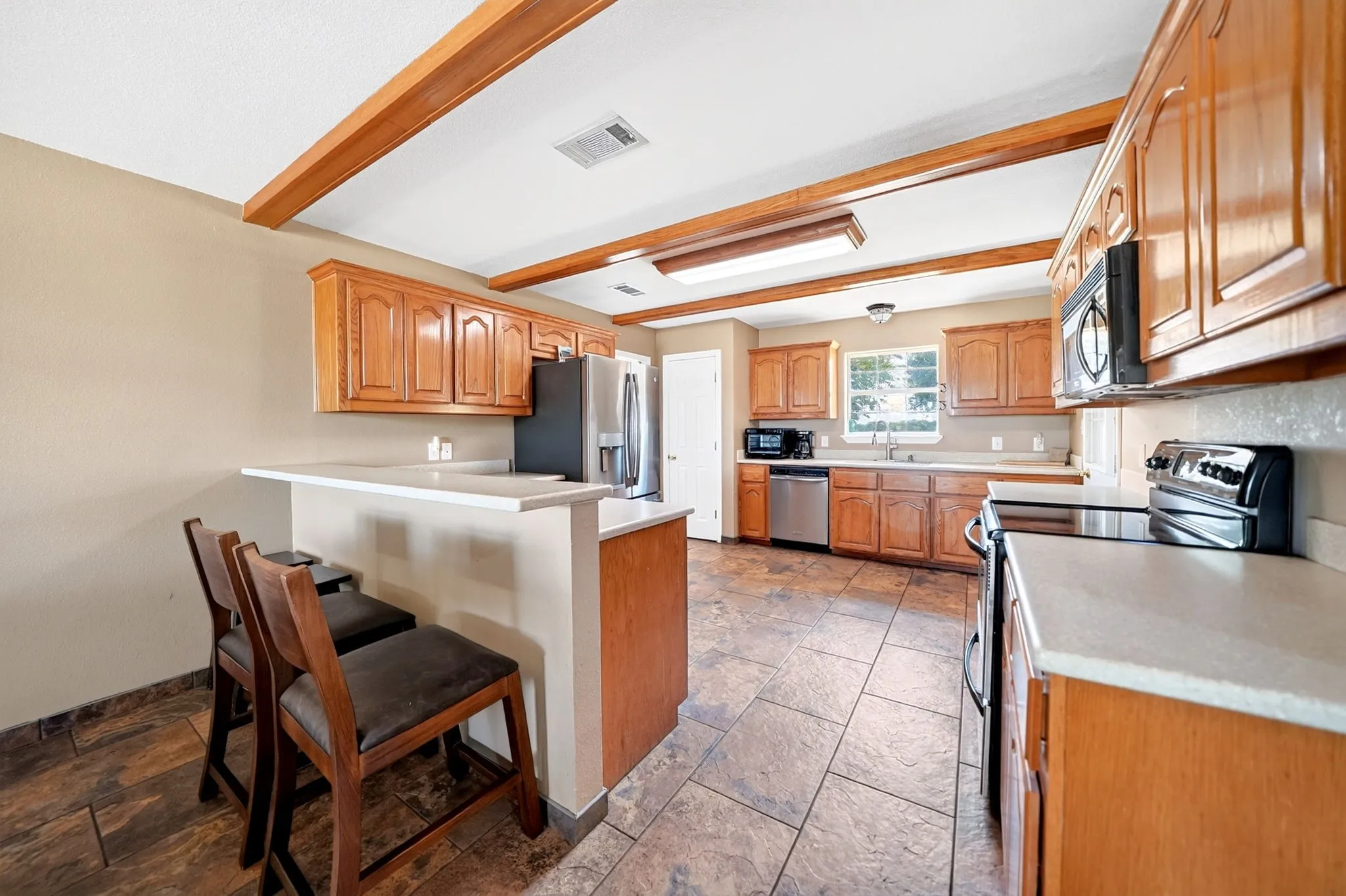 Kitchen featuring warm wood cabinetry, light-toned countertops, and a breakfast bar
