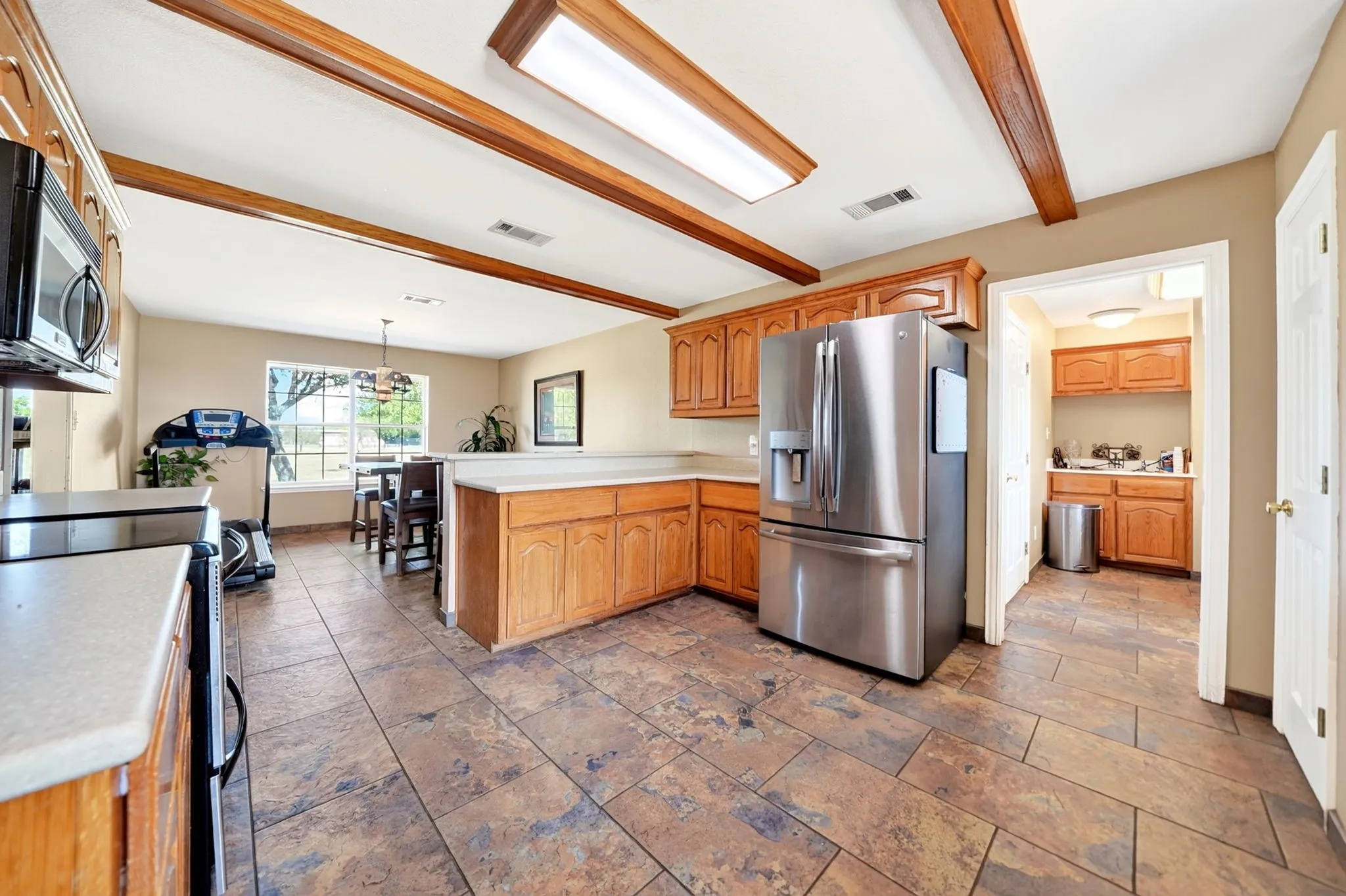 Kitchen featuring wood-finish cabinetry, light countertops, and tile flooring
