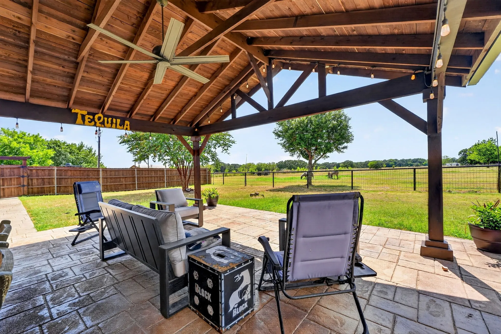 Covered patio with wood ceiling, exposed beams, ceiling fan, and decorative string lights