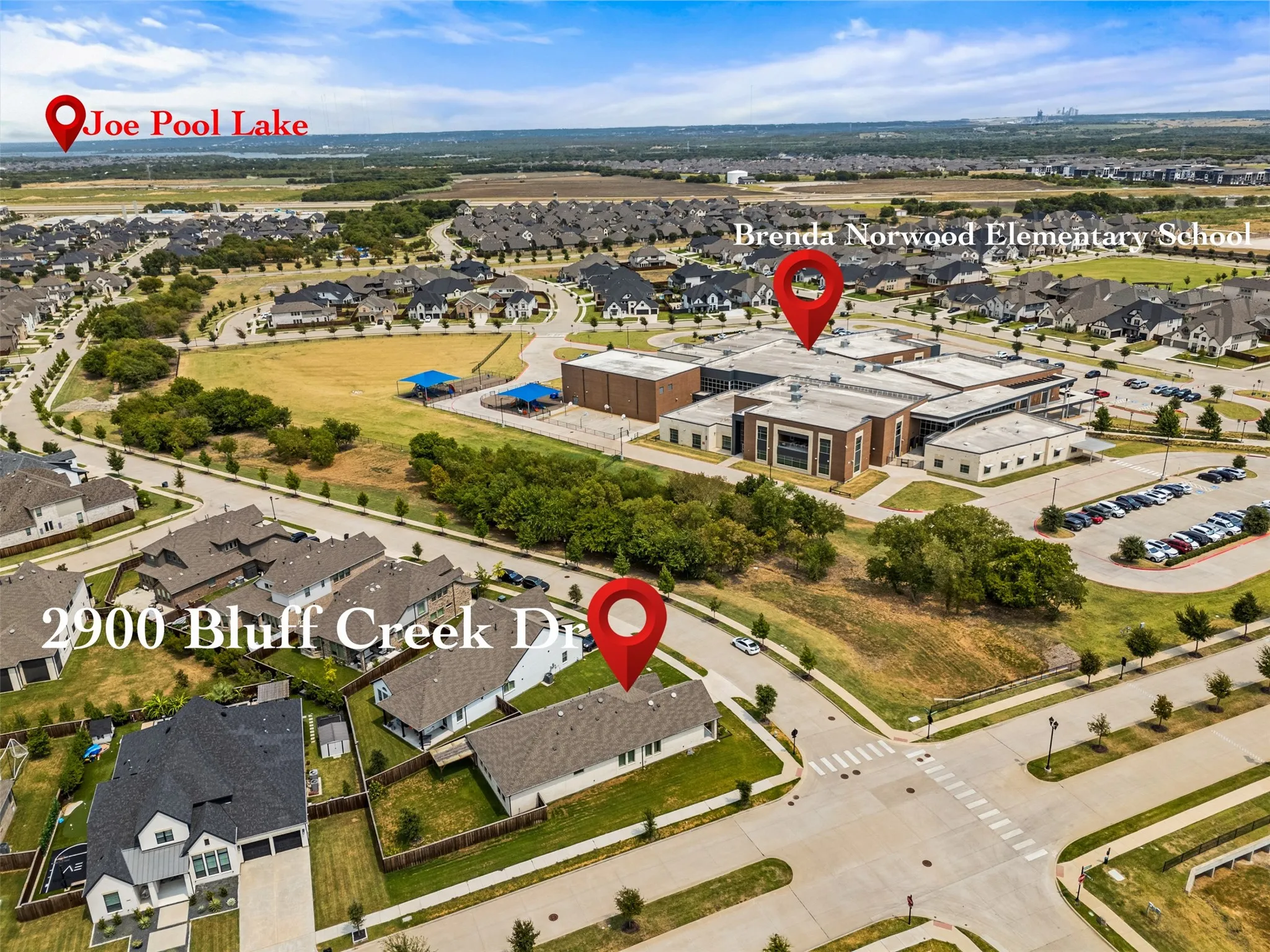 Aerial overview of a residential neighborhood featuring detached homes with varied rooflines and a contemporary elementary school building