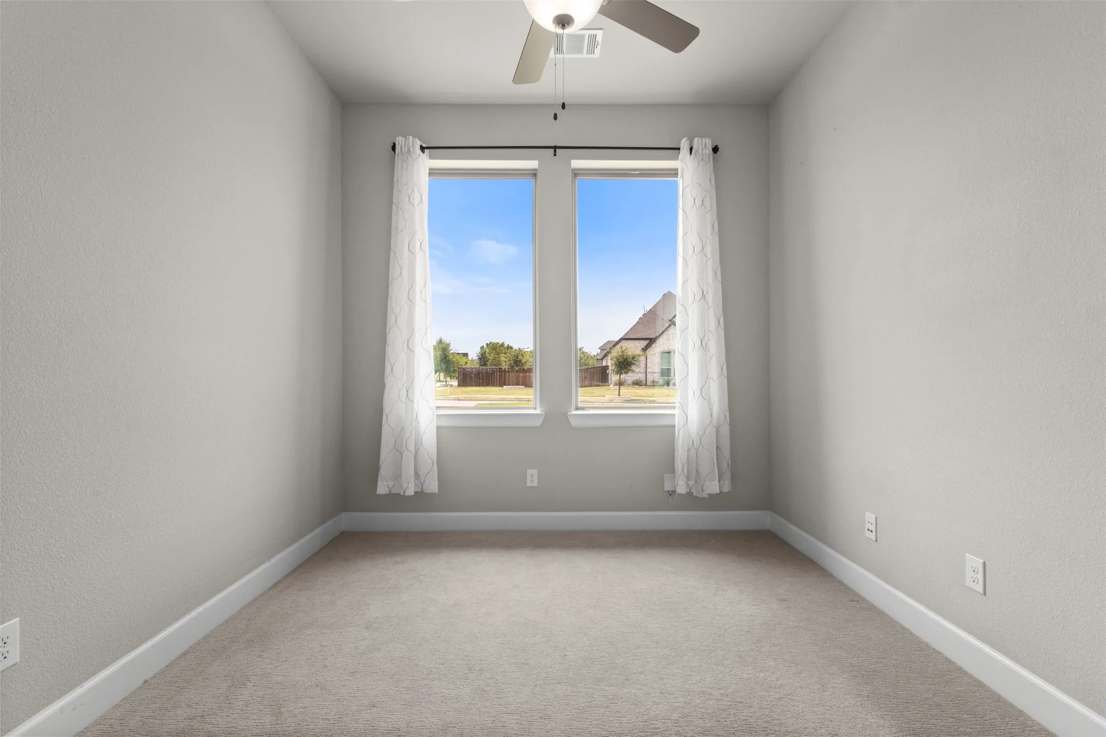 Neutral tone wall finish, carpeted flooring, and a ceiling fan light fixture