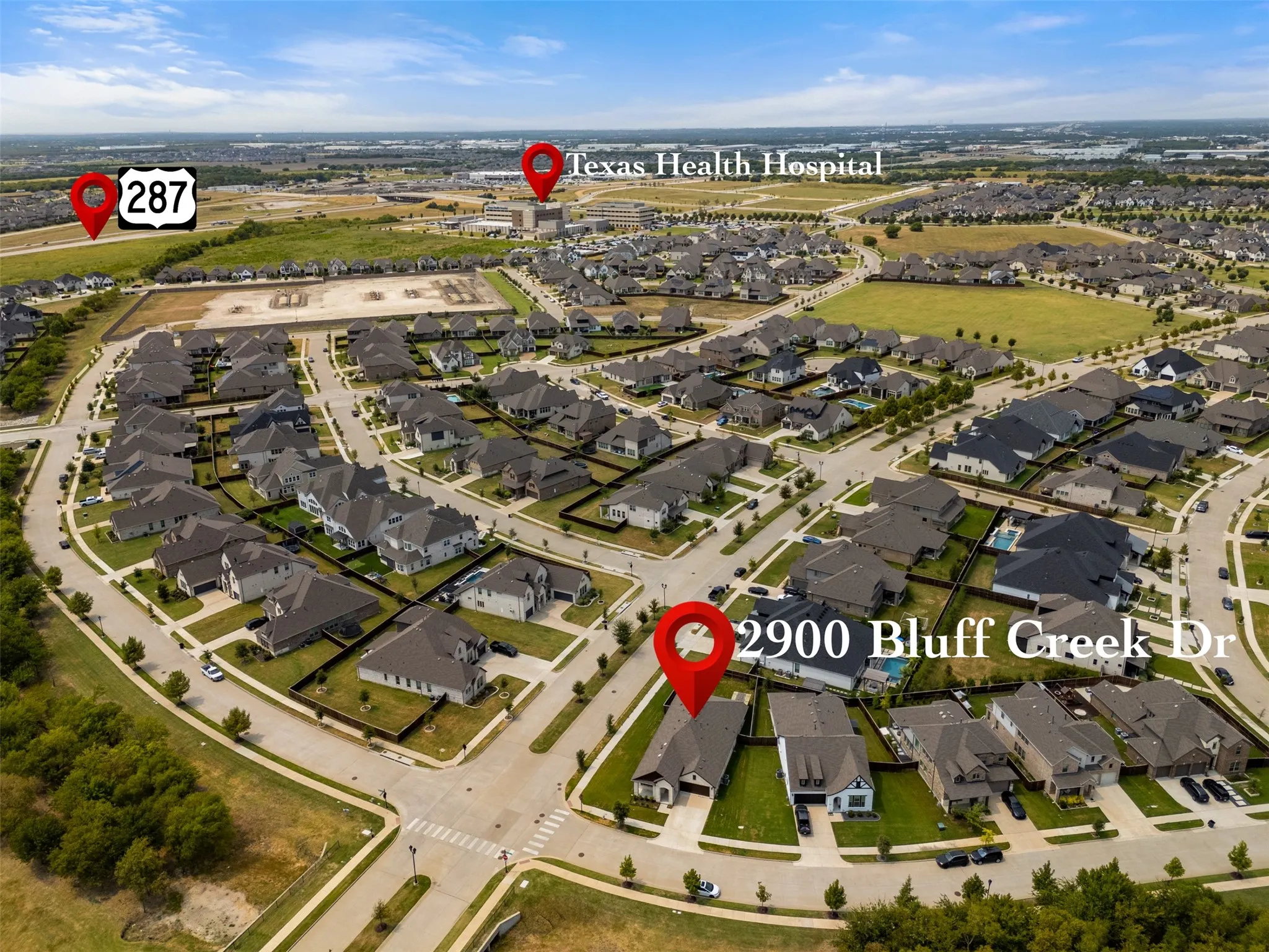 Aerial perspective of a residential neighborhood with numerous single-family homes, paved streets, and green spaces