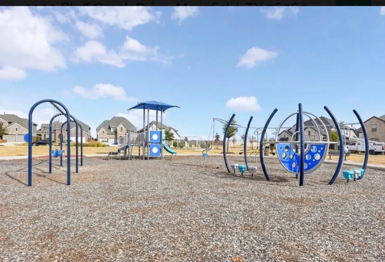 Outdoor playground featuring multiple play structures, swings, and a slide, all set on a wood chip surface