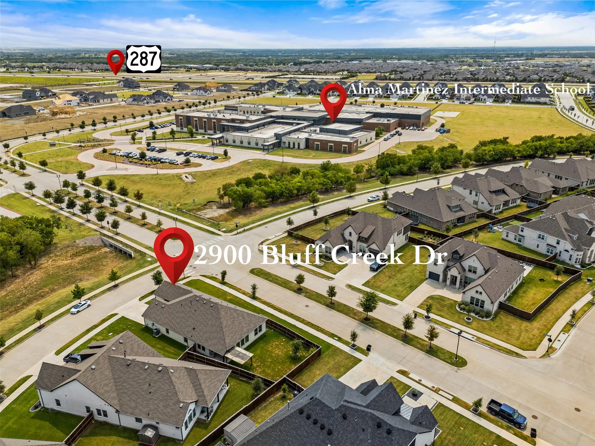 Aerial perspective of a residential neighborhood with numerous single-family homes, a large school building, and paved roadways