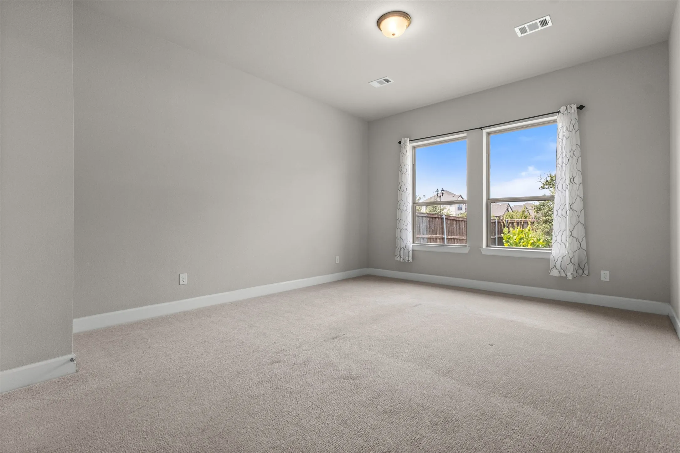 Neutral tone wall paint, carpet flooring, dual windows, and ceiling-mounted lighting