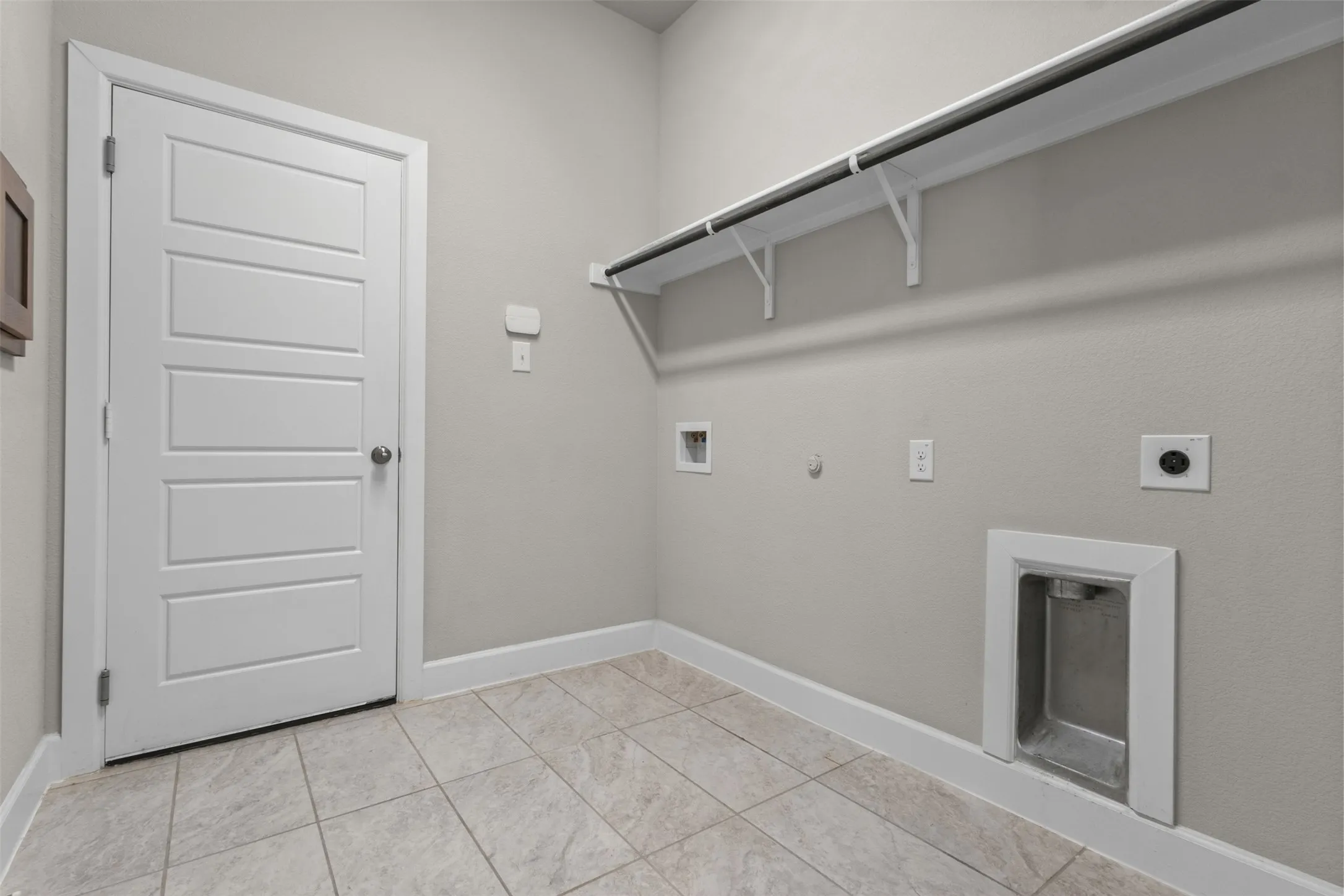 Neutral-toned tile flooring, light gray walls, white trim, and a white five-panel interior door