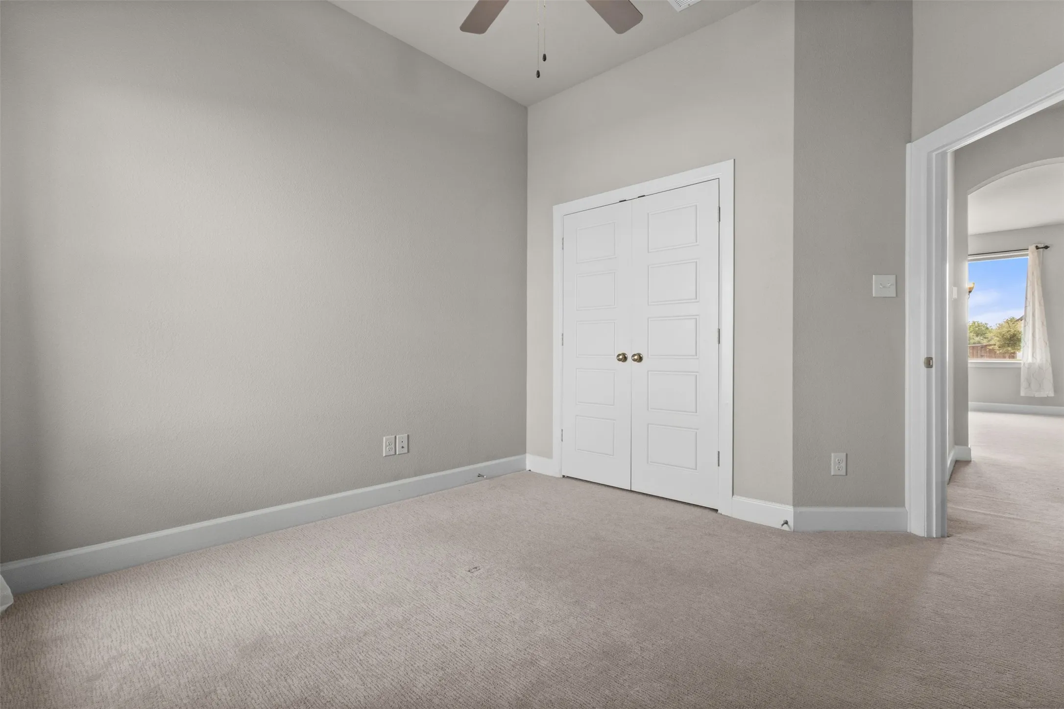 Neutral-toned carpeting throughout, crisp white trim, and a ceiling fan