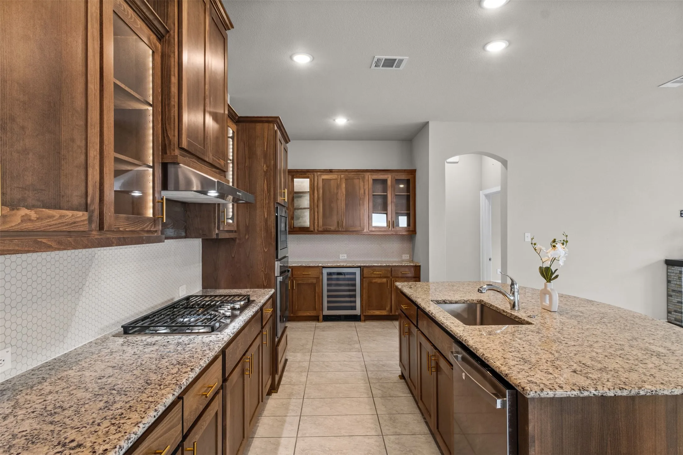 Kitchen featuring wood cabinetry, stone countertops, a built-in gas cooktop with stainless steel vent hood, a tiled backsplash, and recessed lighting