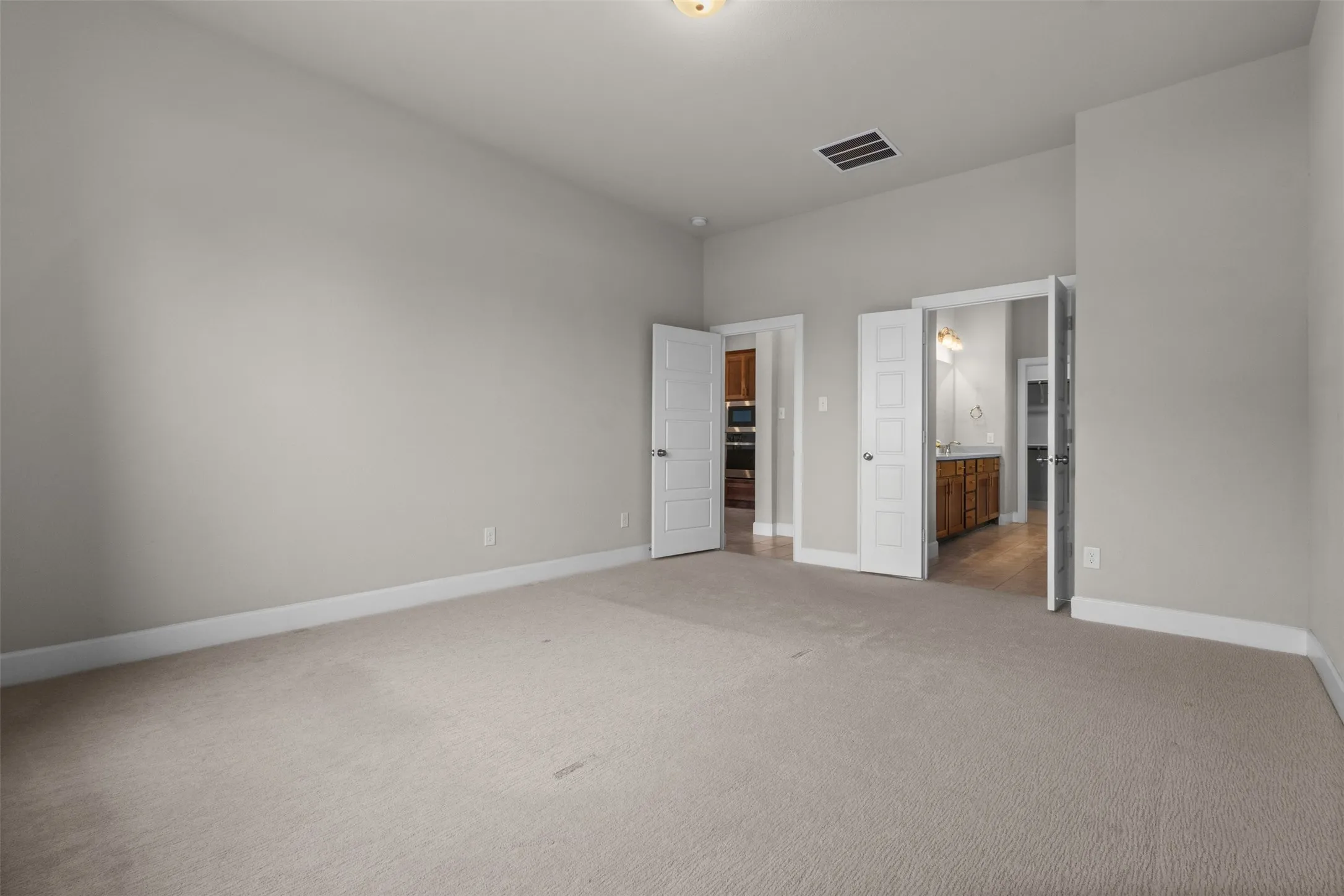 Expansive room with neutral carpeting, light gray walls, and white trim