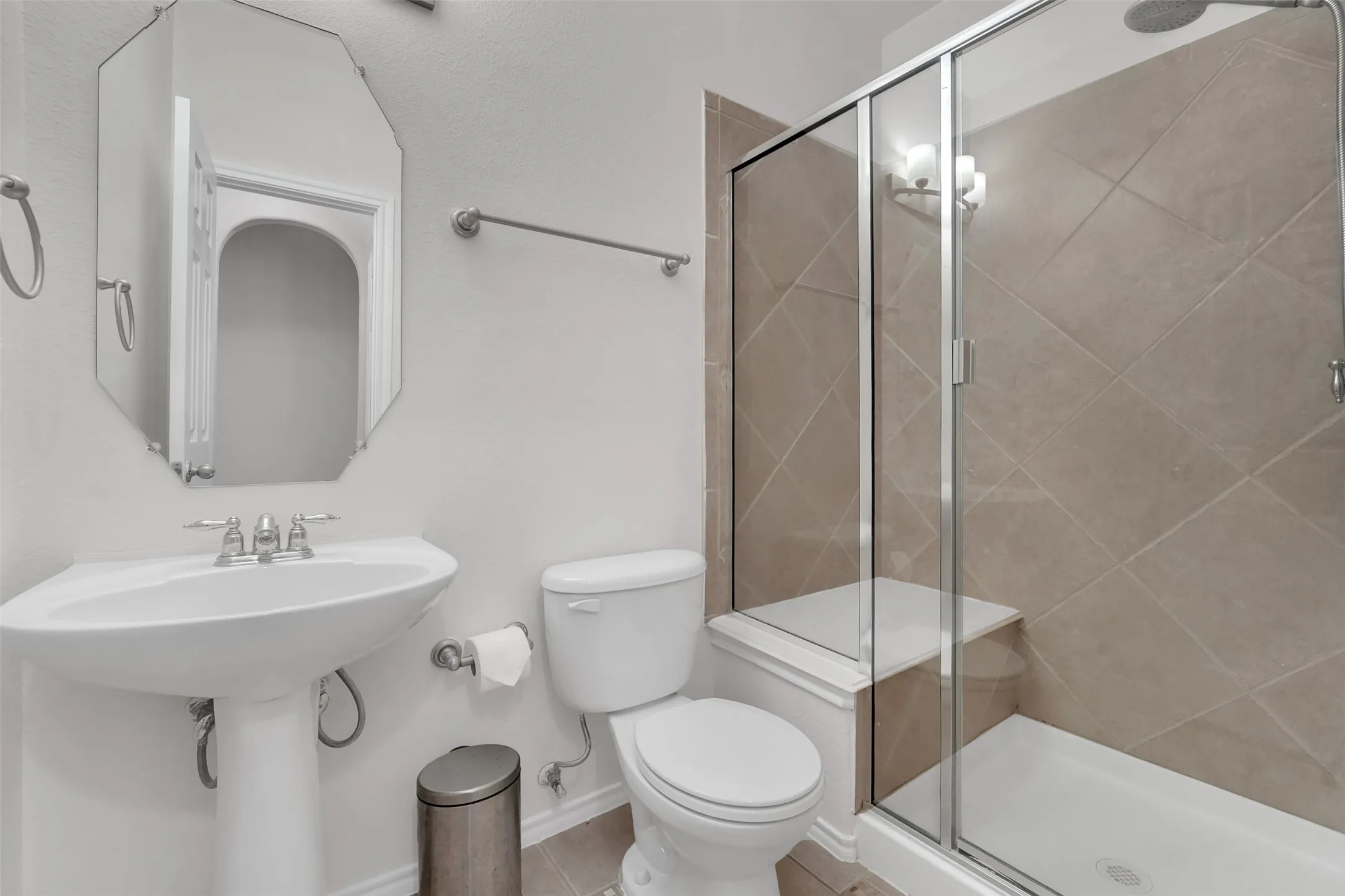 Pedestal sink with chrome fixtures and an octagonal mirror