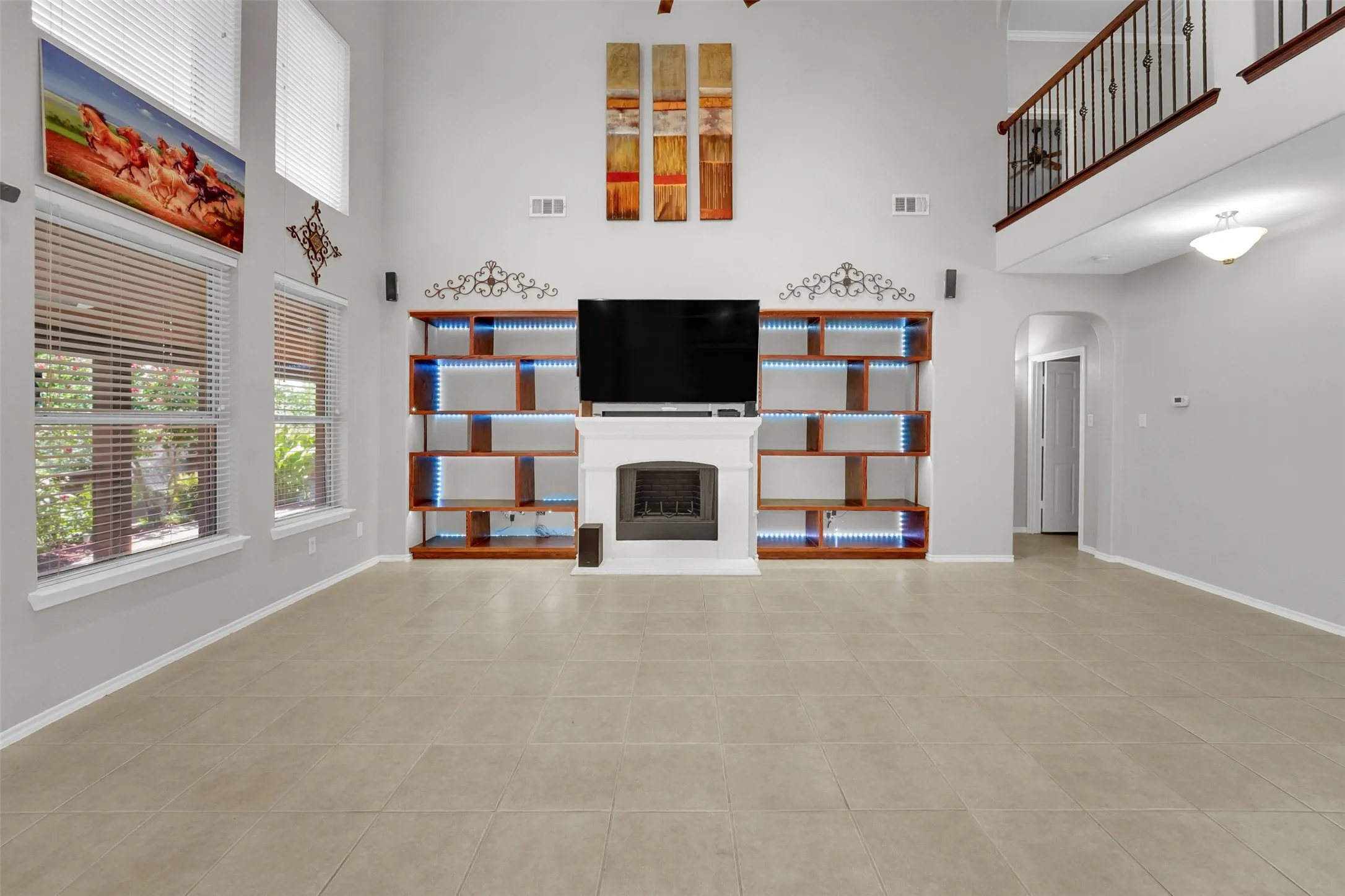 Two-story living area with high ceilings, tile flooring, a fireplace, and built-in shelving