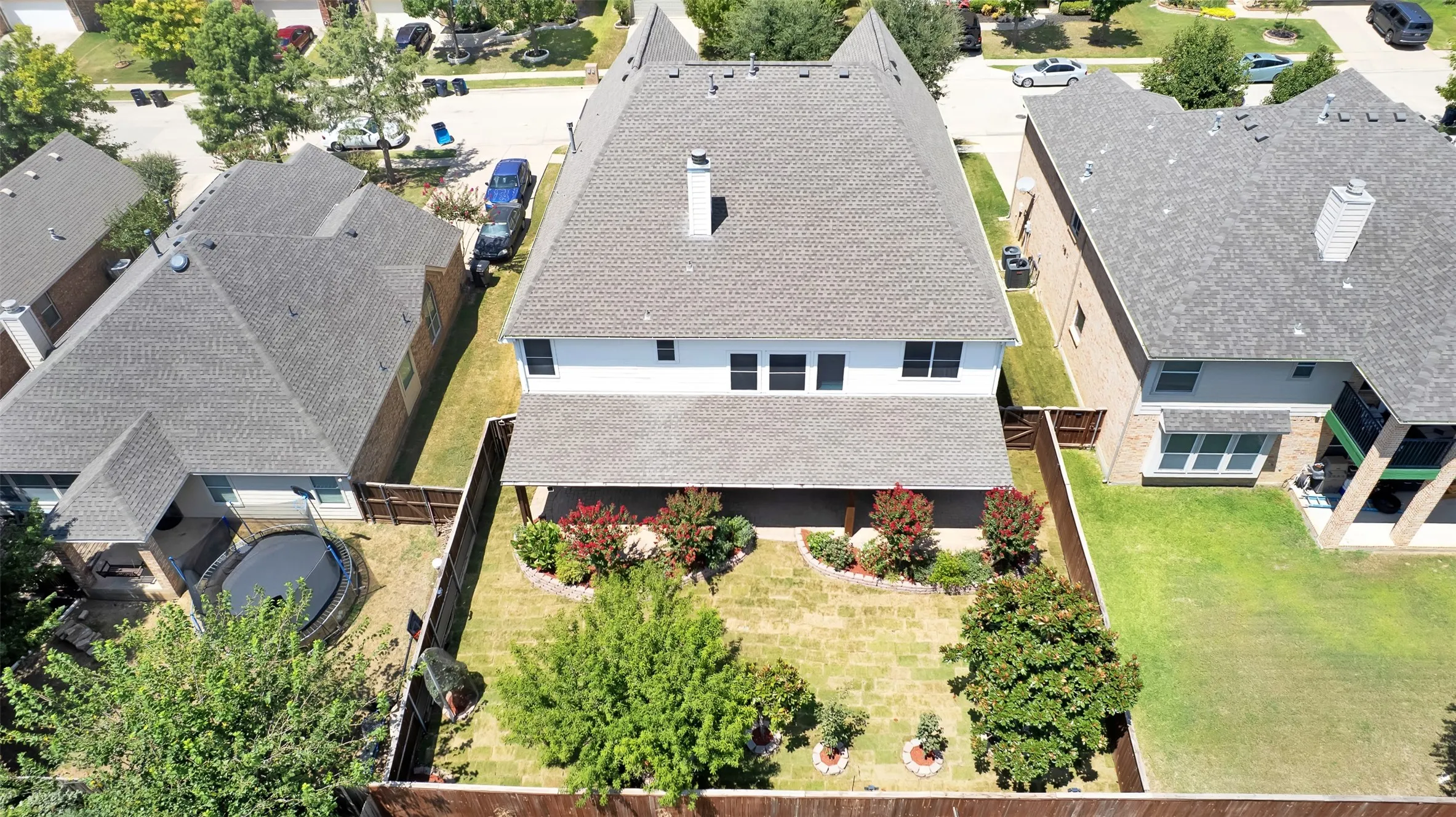 Fenced backyard featuring an expansive lawn, covered patio, and mature landscaping