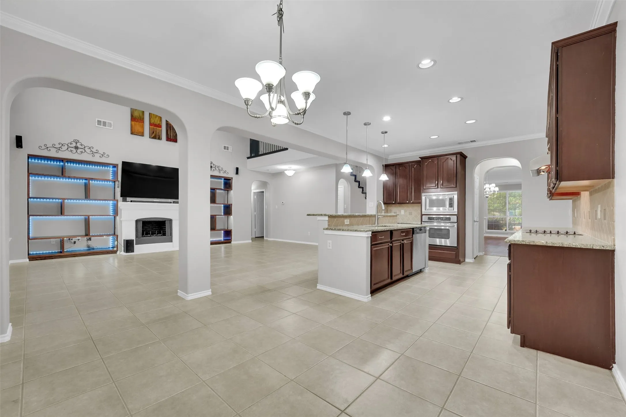 Spacious open-concept living area featuring tile flooring, a fireplace, and built-in shelving