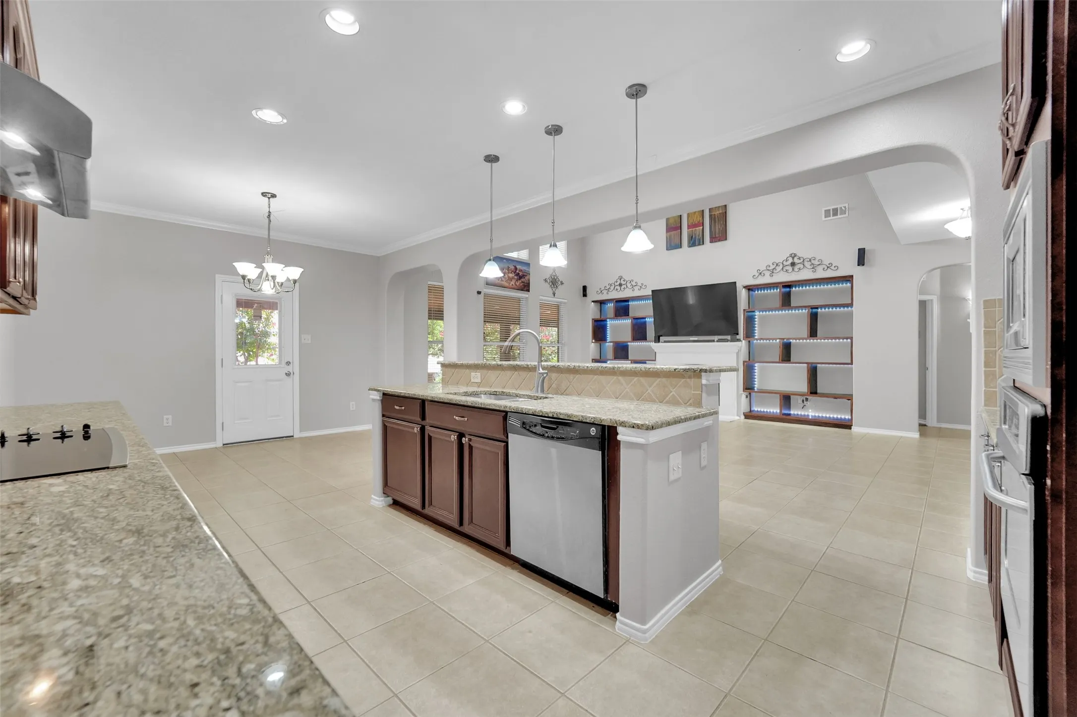 Central kitchen island with granite countertops, stainless steel appliances, and pendant lighting