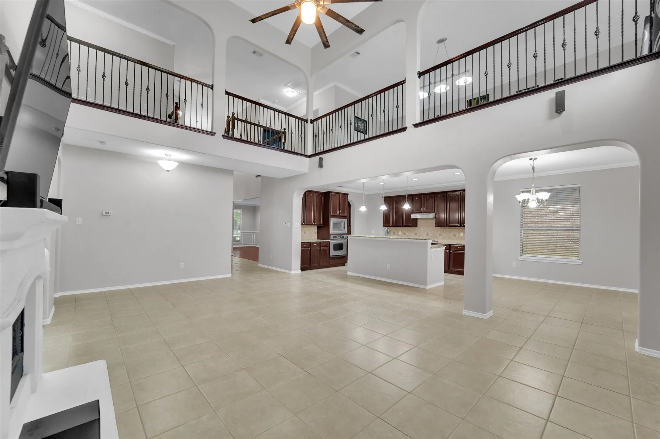 Two-story living area with high ceilings, tile flooring, and decorative wrought iron railings