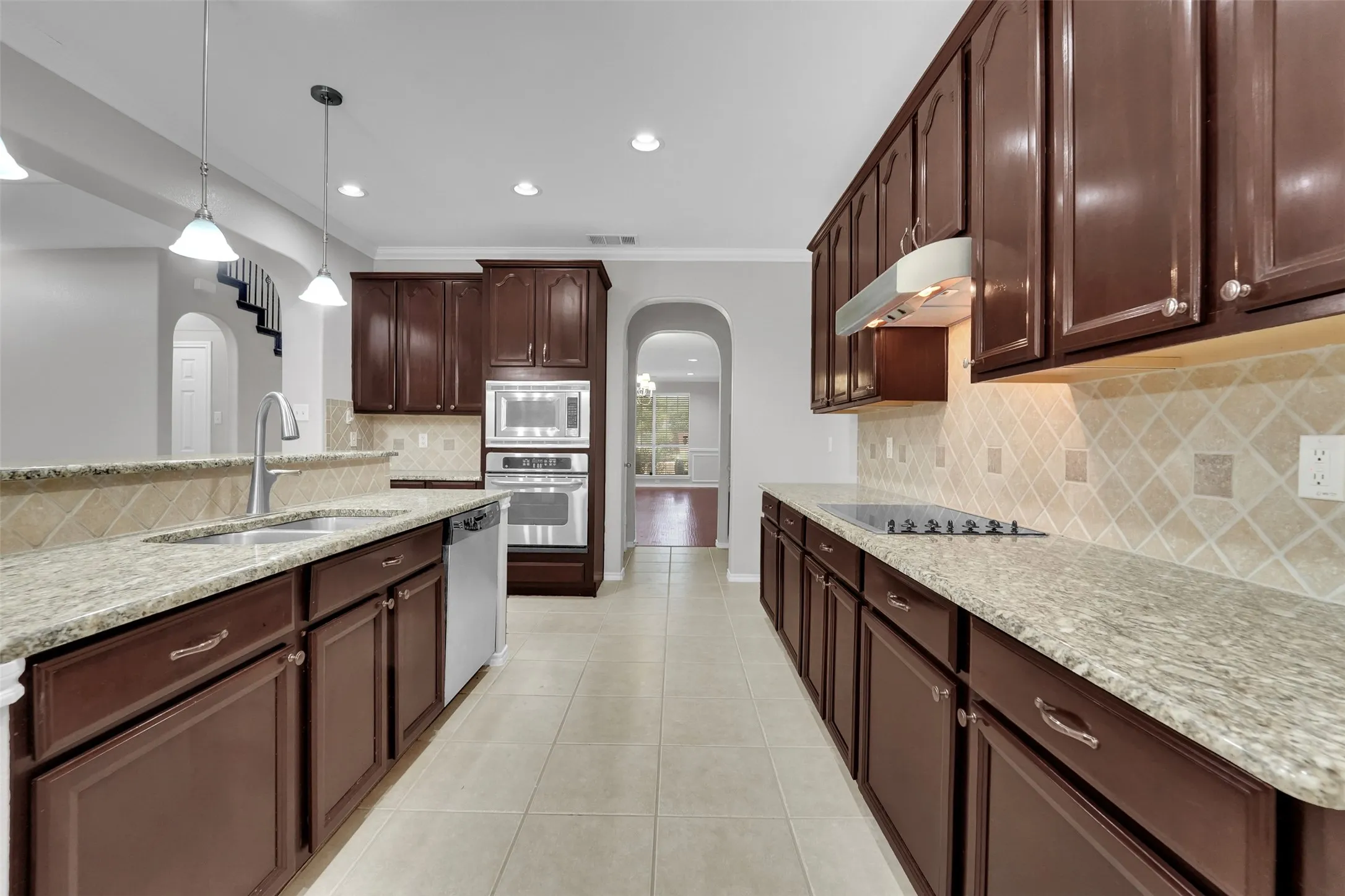 Expansive kitchen with granite countertops, rich wood cabinetry, stainless steel appliances, and a tiled backsplash