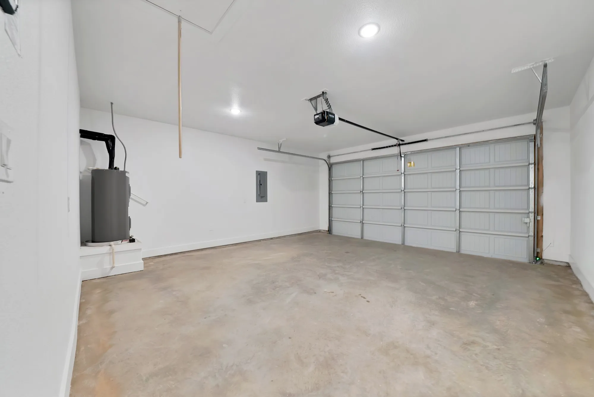 Concrete floor, white walls, overhead lighting, garage door, automatic garage door opener