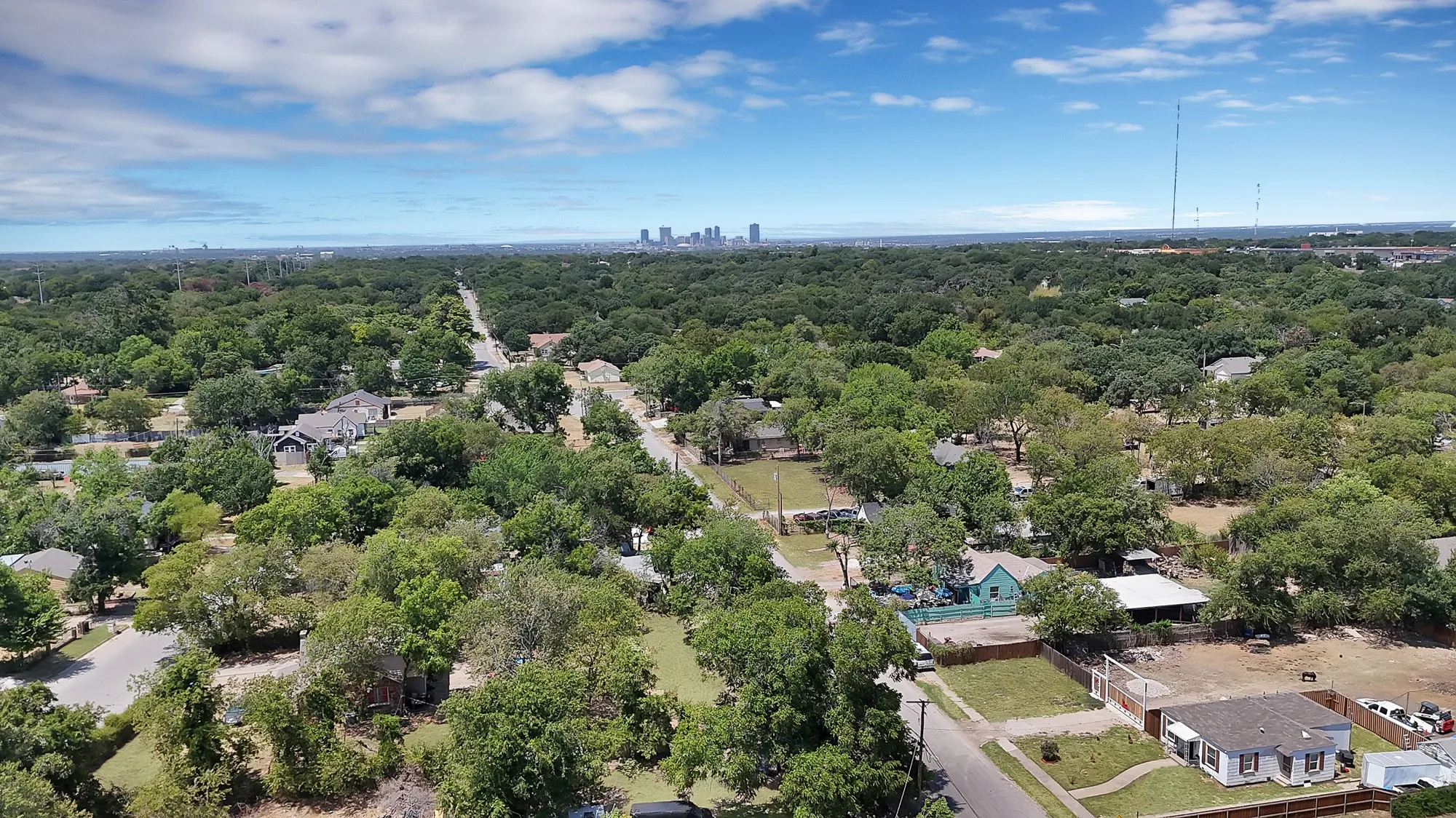 Aerial perspective showcasing a residential area with extensive tree coverage and distant city skyline