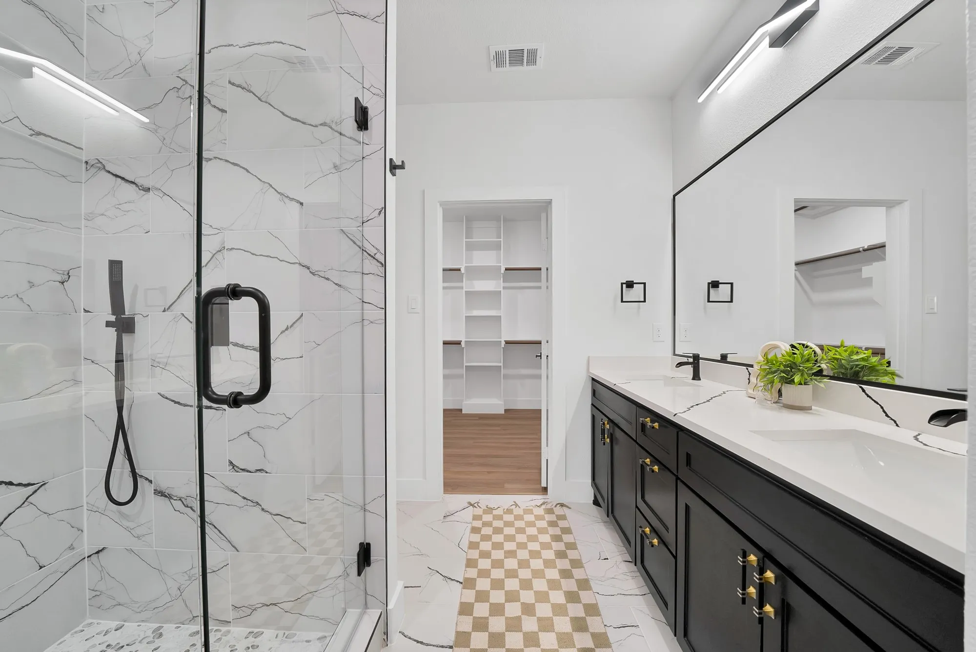 Frameless glass shower enclosure with marbled tile surround