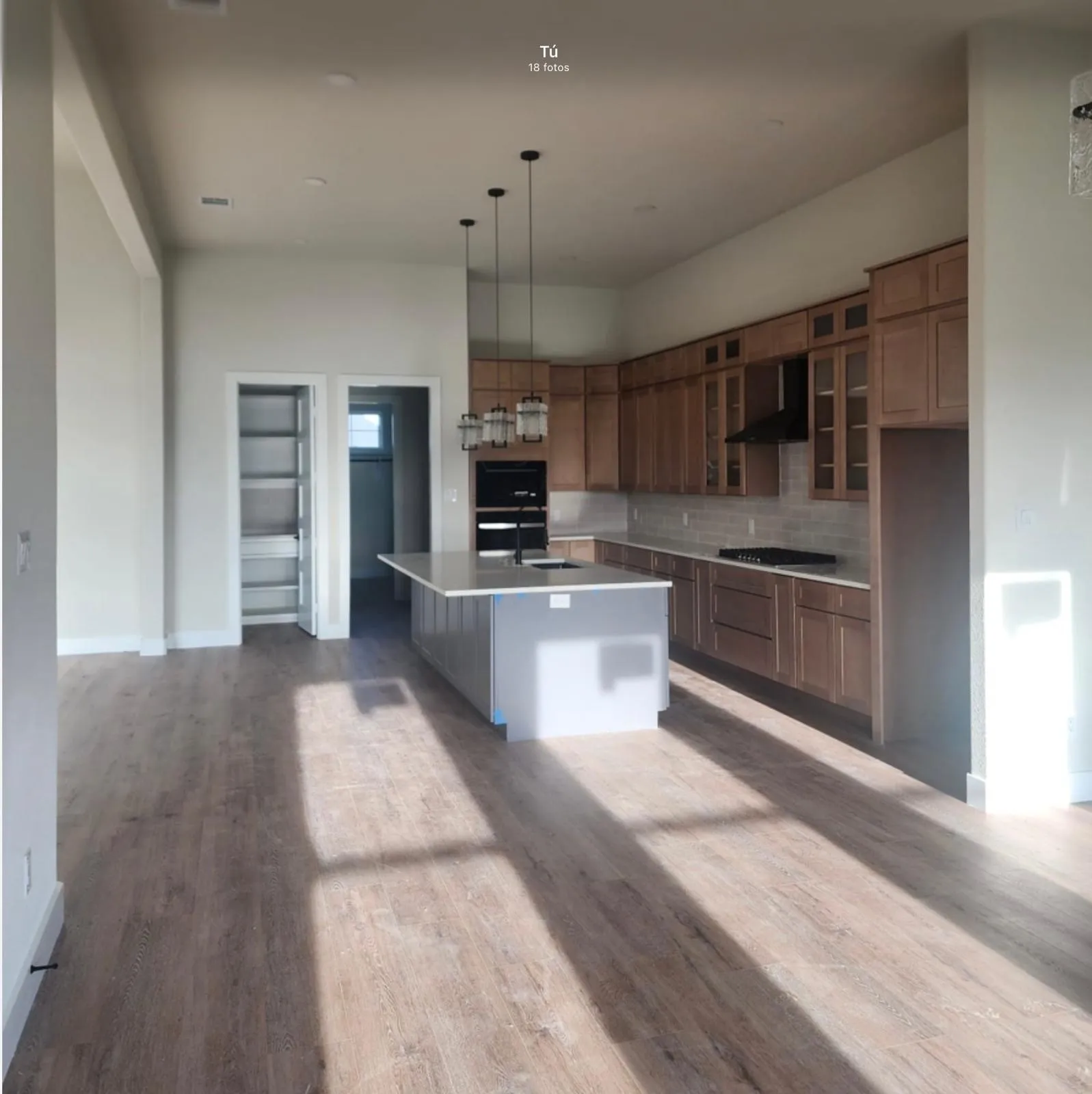 Open-concept kitchen with a central island, light wood-finish flooring, and high ceilings