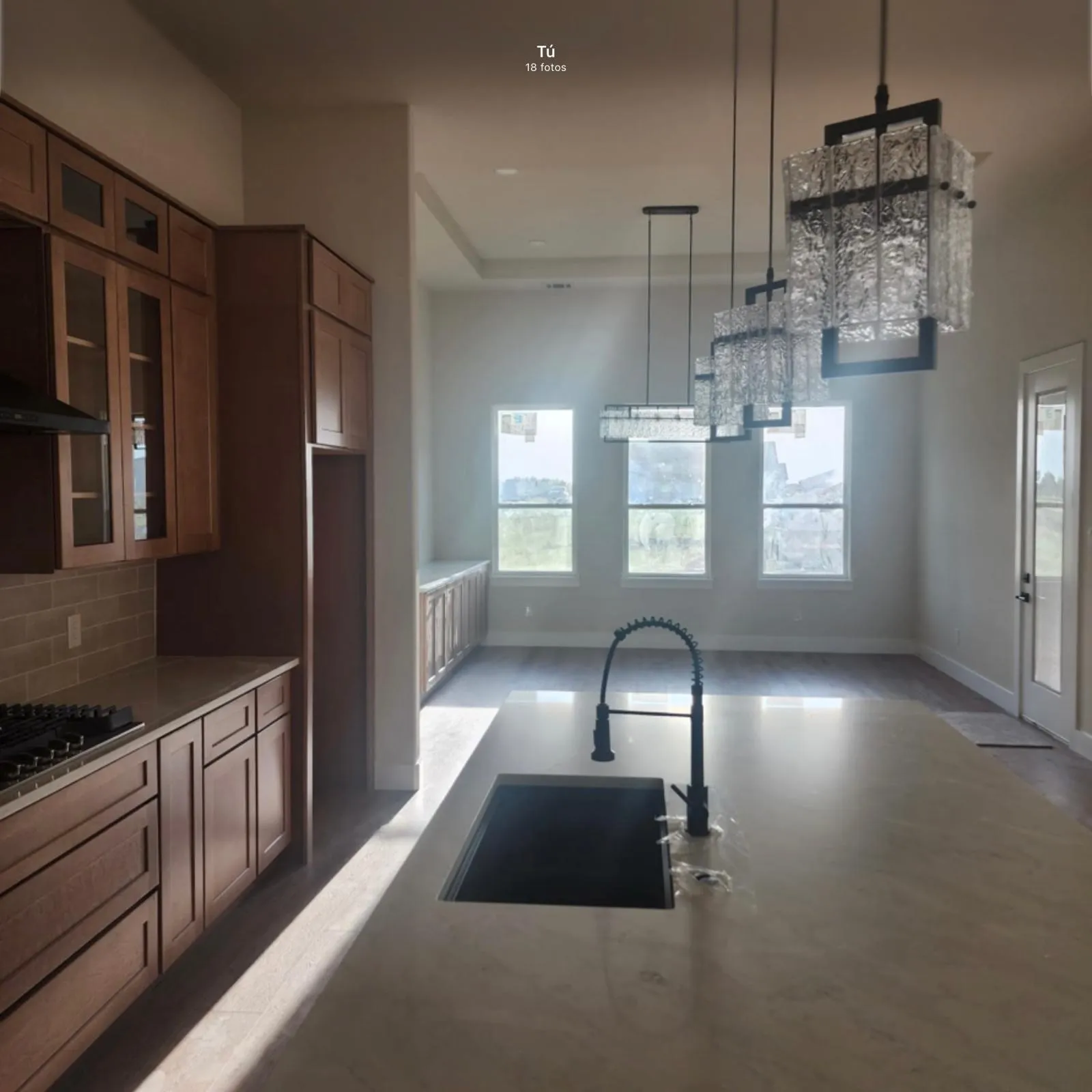 Spacious kitchen and dining area featuring an expansive island with an undermount sink and a matte black pull-down faucet