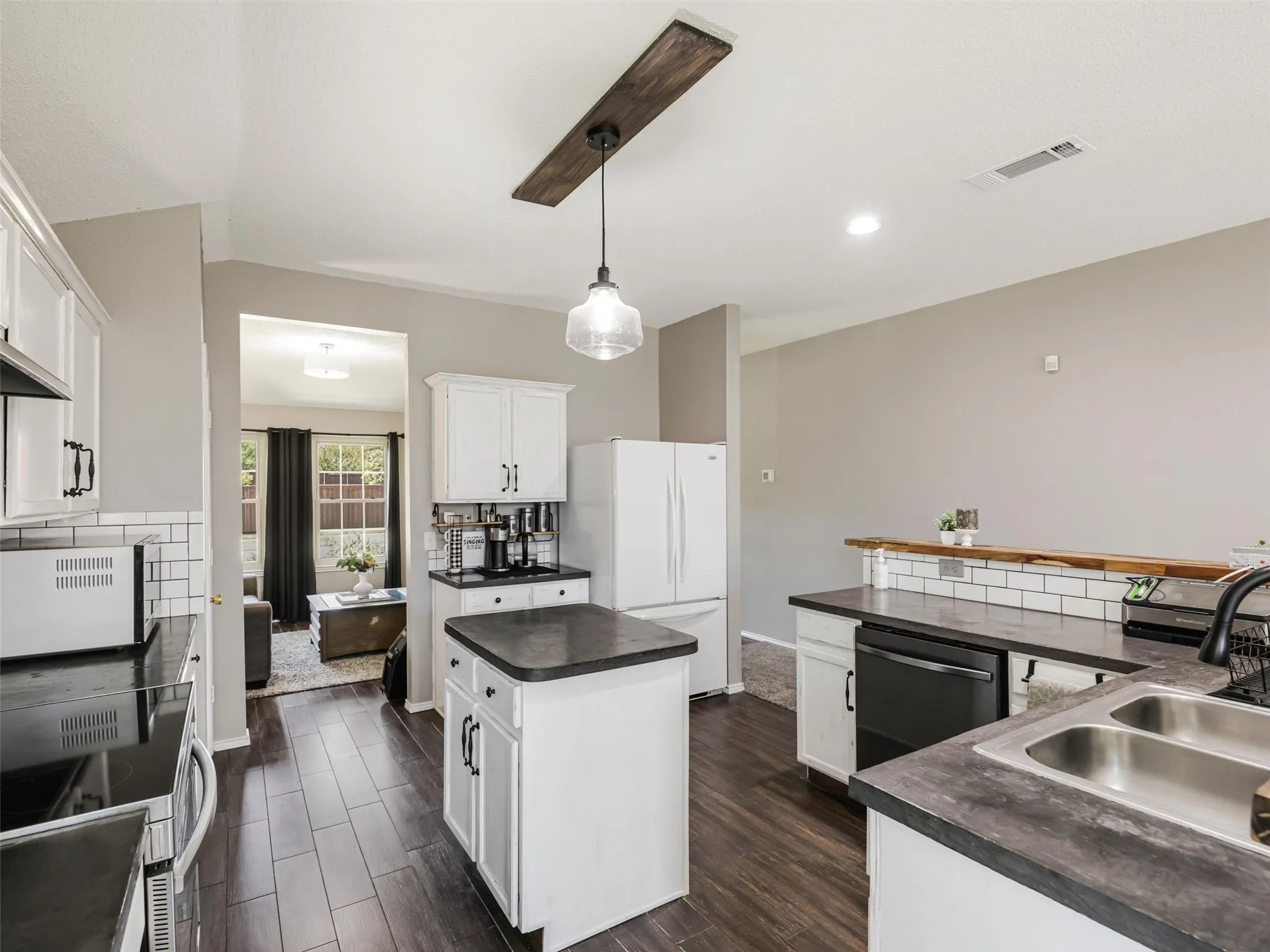 Modern kitchen featuring white cabinetry, dark wood-finish flooring, and stainless steel appliances including a double oven range