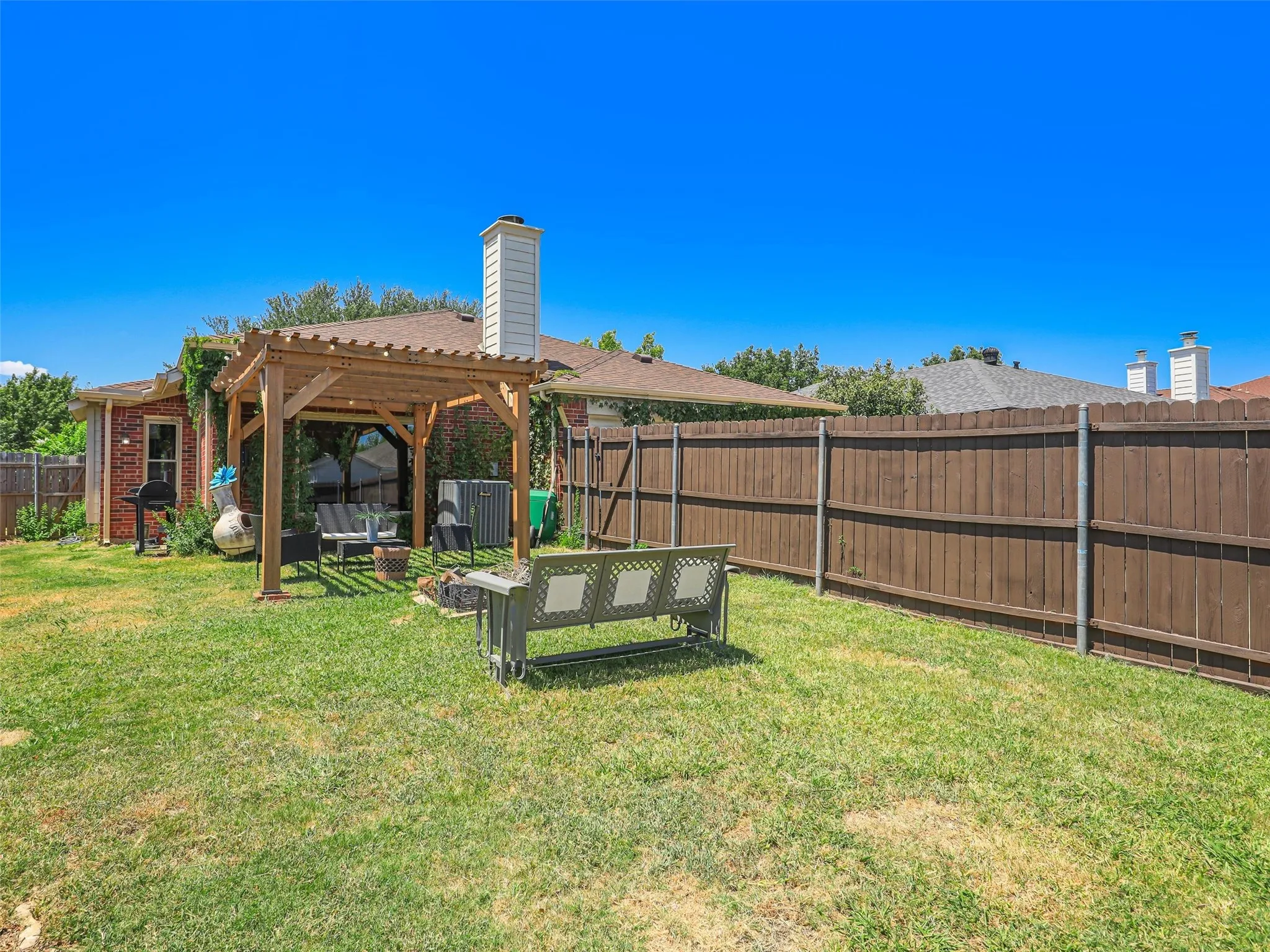 Expansive backyard featuring a wood pergola and a privacy fence