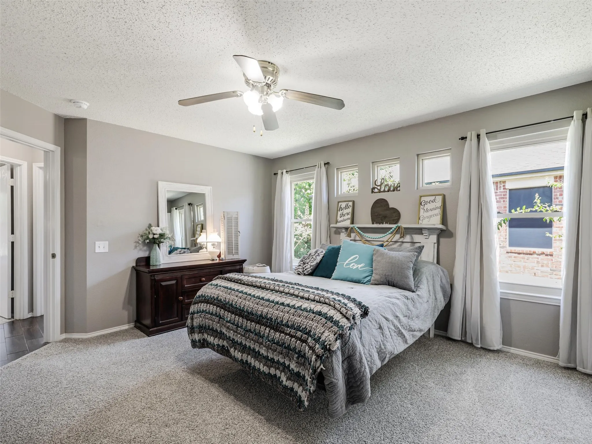 Spacious primary bedroom with wall-to-wall carpeting, ceiling fan with integrated lighting, and dual glass doors opening to outdoor space