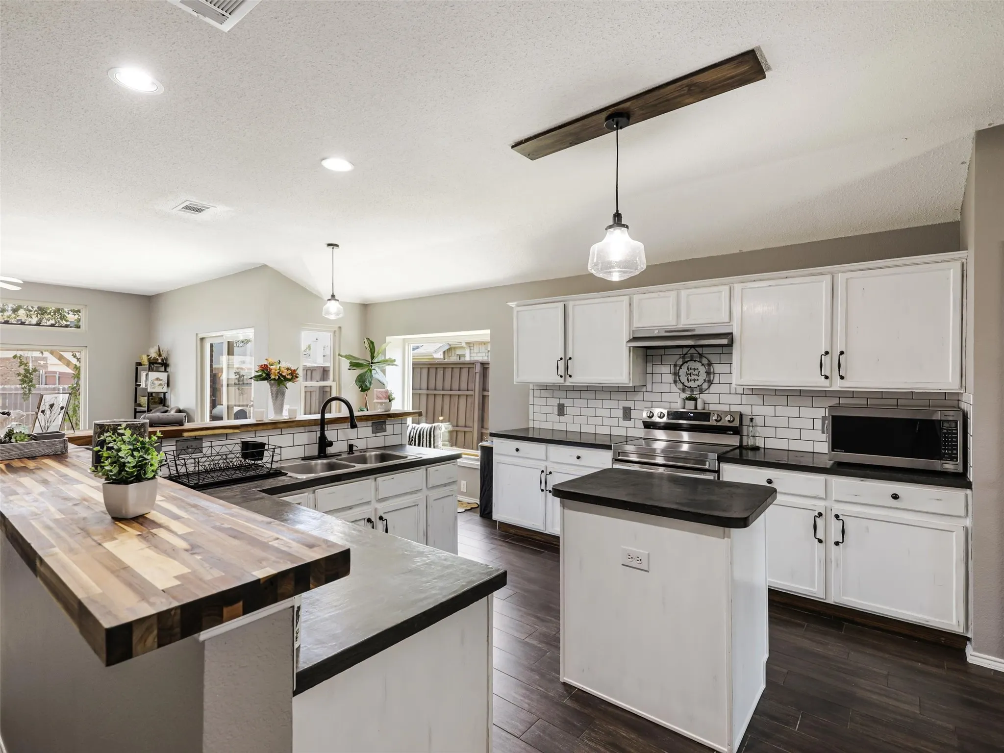 Kitchen featuring white cabinetry, dark countertops, a subway tile backsplash, and dark wood-finish flooring