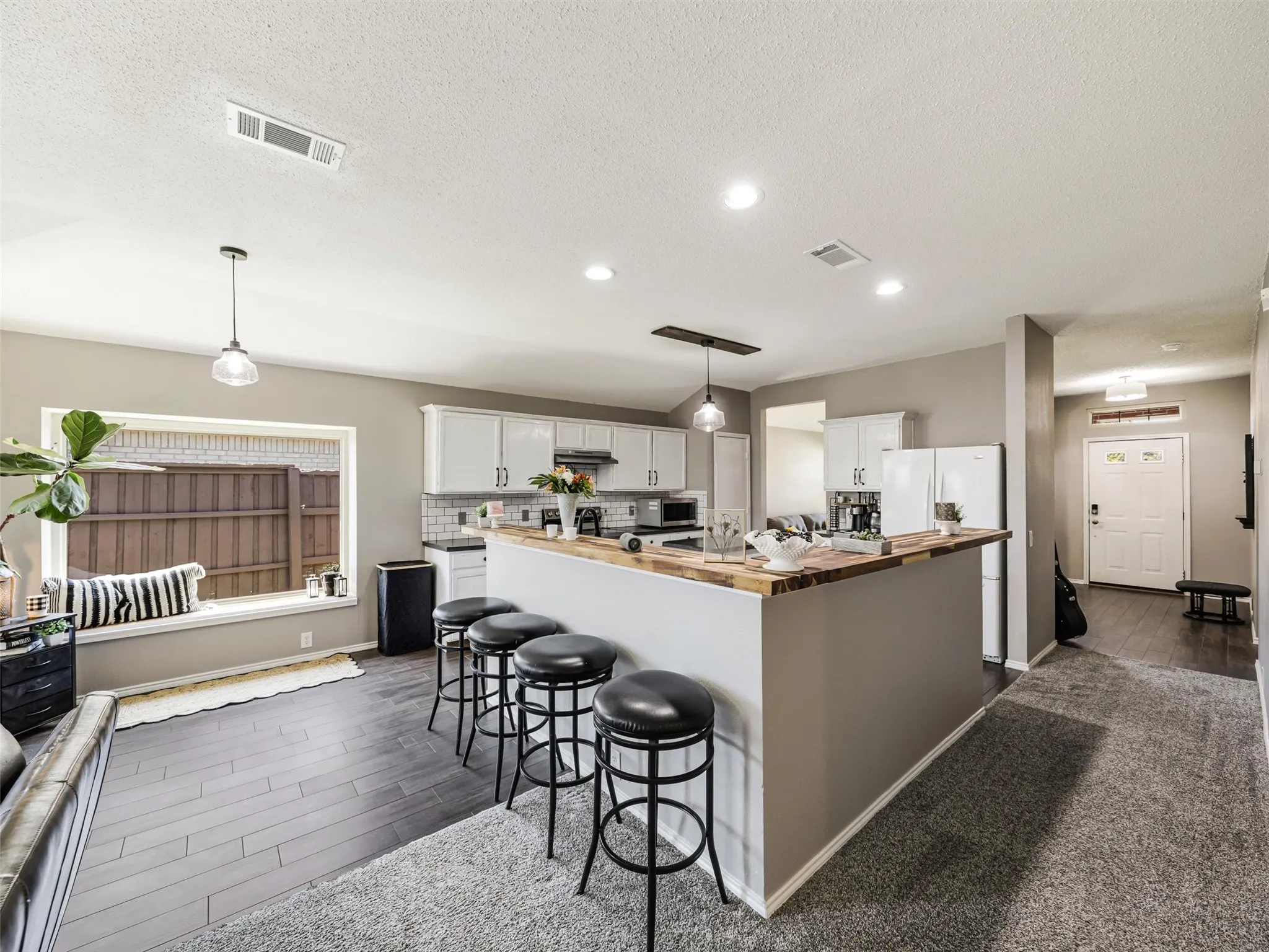 Kitchen featuring white cabinetry, a butcher block-style countertop, subway tile backsplash, and a breakfast bar