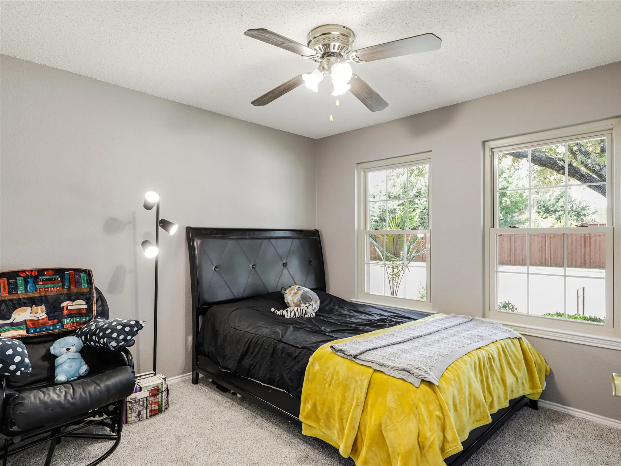 Ceiling fan with light kit, two large windows, and wall-to-wall carpeting