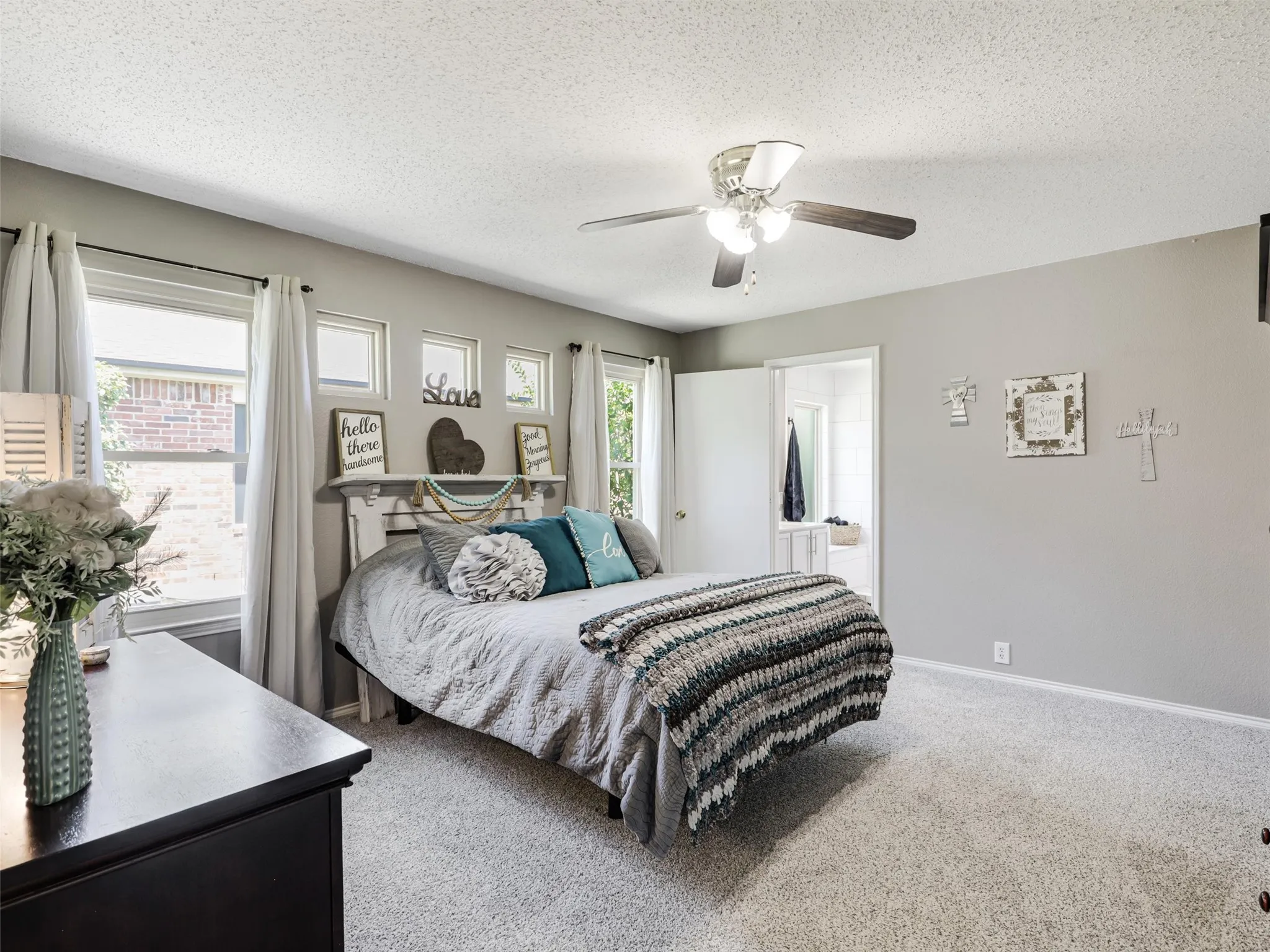 Carpeted room with a ceiling fan, multiple windows, and light gray wall color