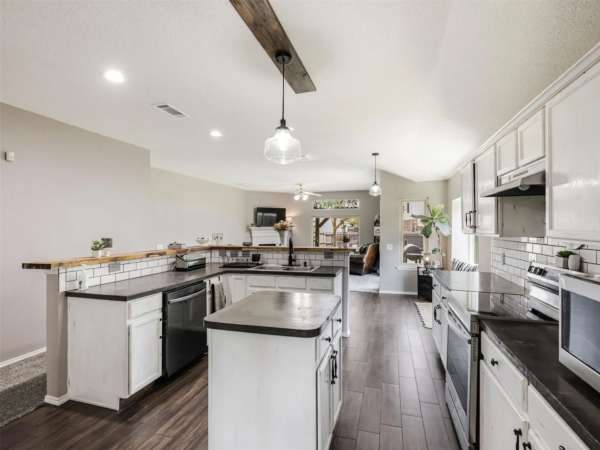 White cabinetry, subway tile backsplash, dark countertops, and wood-finish flooring